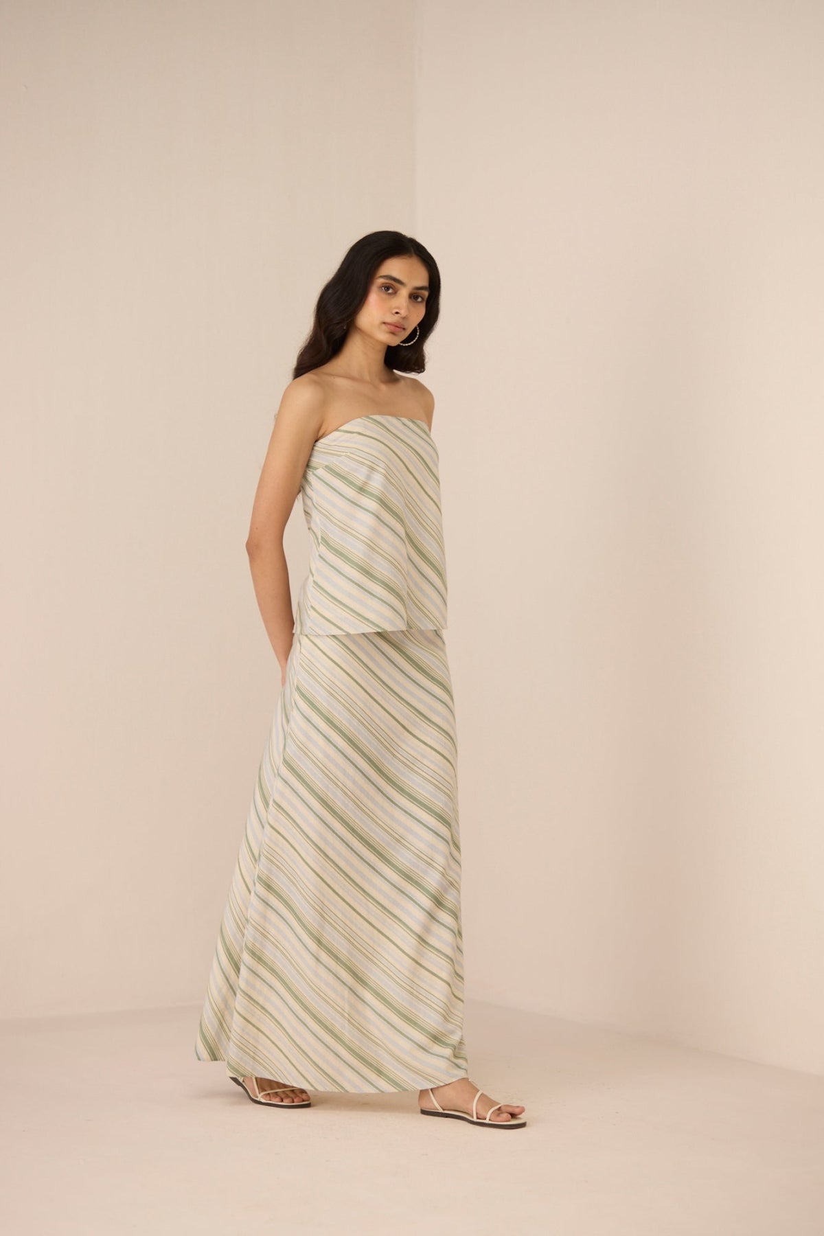 Woman wearing a strapless, long, patterned dress against a plain background Calling June