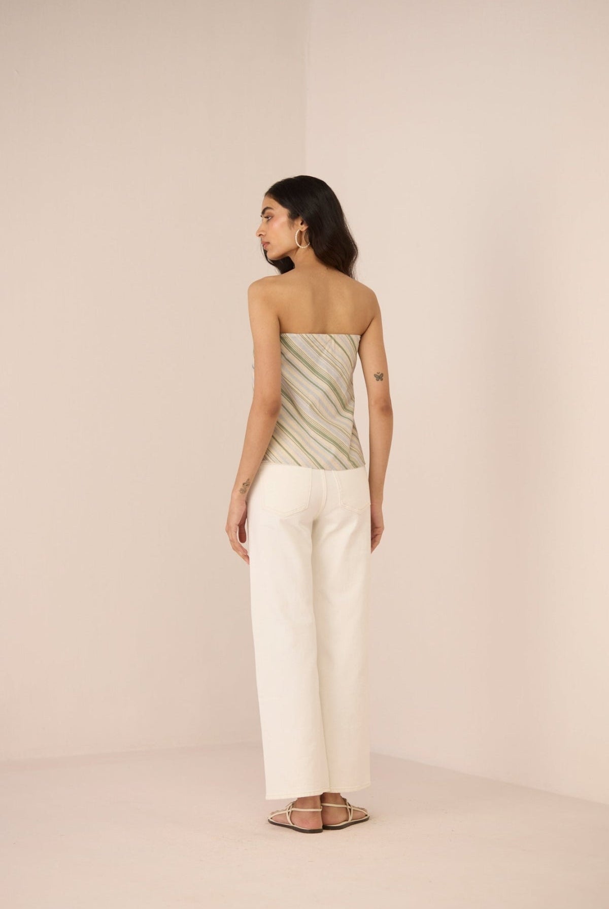 Woman wearing a strapless top and wide-leg pants on a beige background Calling June