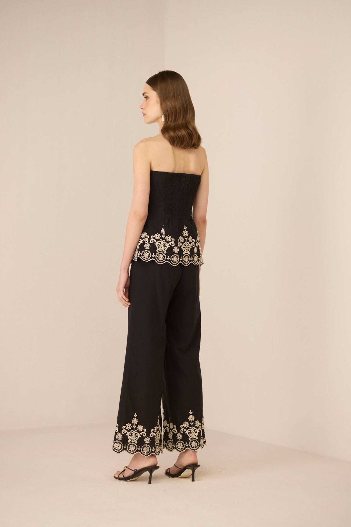 Black strapless top and pants with gold embroidery on a beige background Calling June