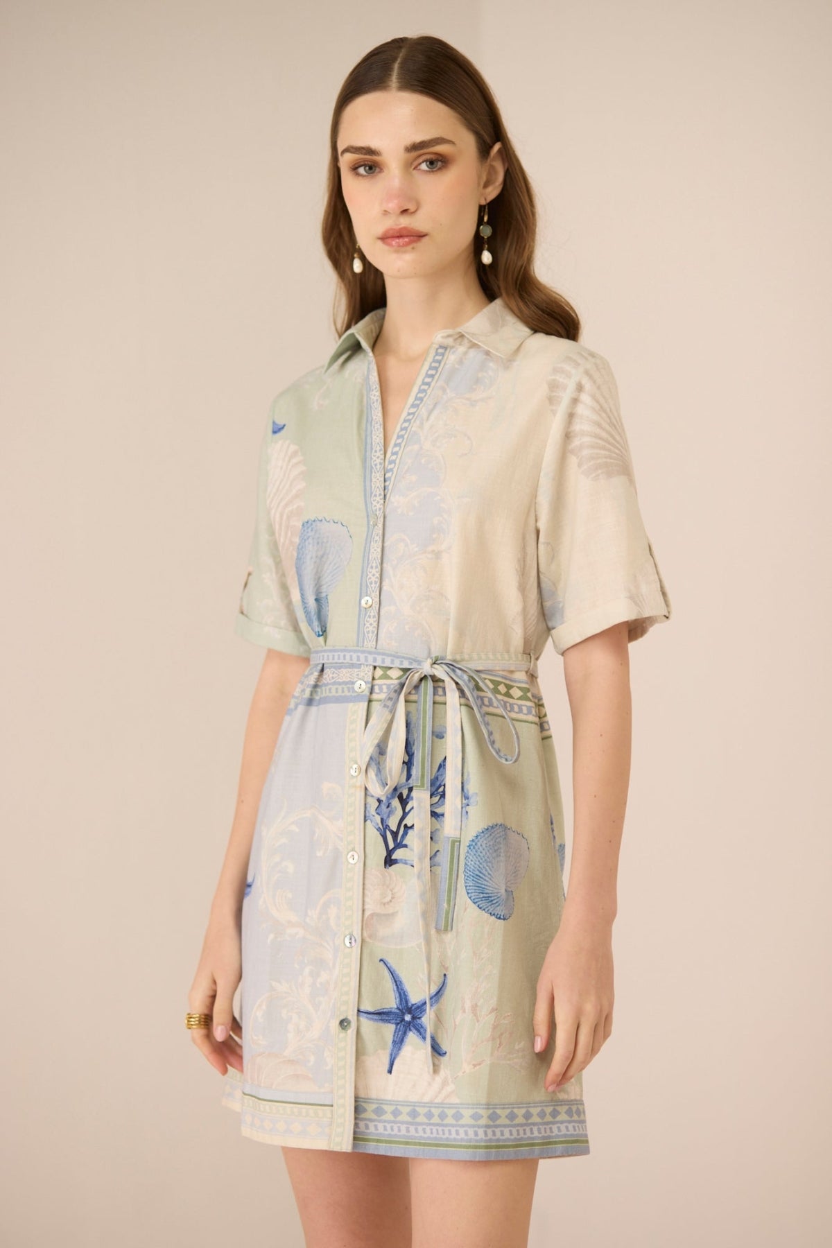 Woman wearing a short-sleeve dress with blue sea-themed patterns on a beige background Calling June