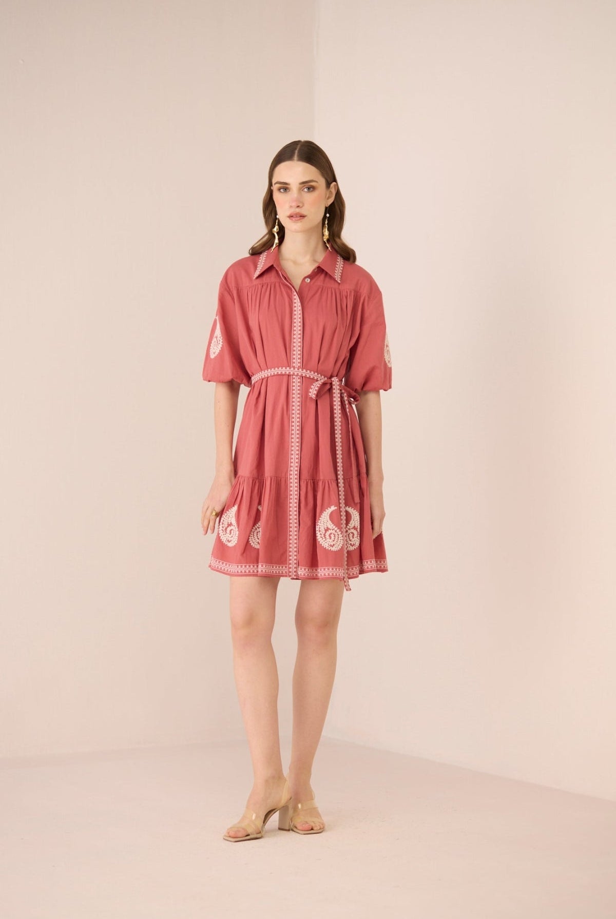 Woman wearing a pink dress with white patterns on a beige background Calling June