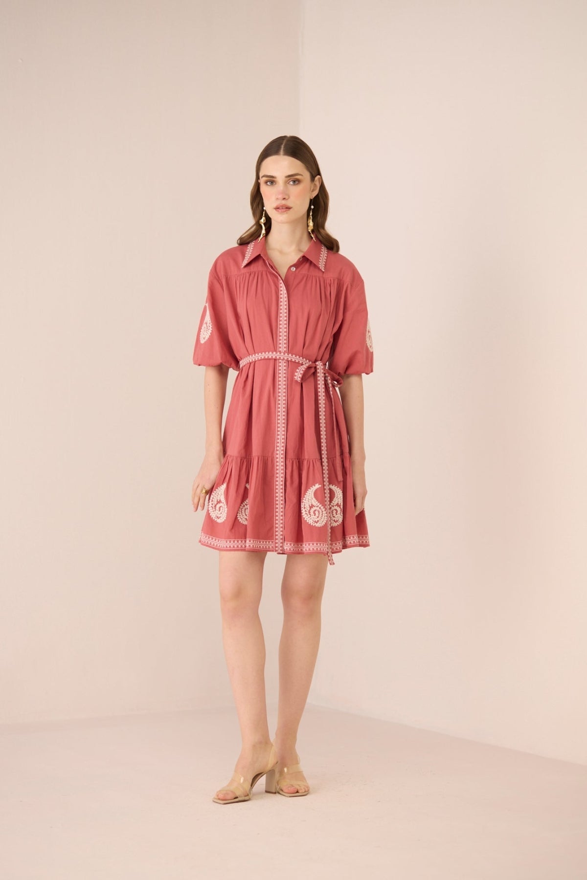 Woman wearing a pink dress with white patterns on a beige background Calling June