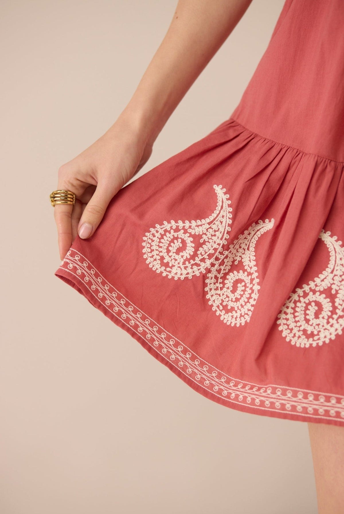 Red dress with white embroidery on a beige background Calling June