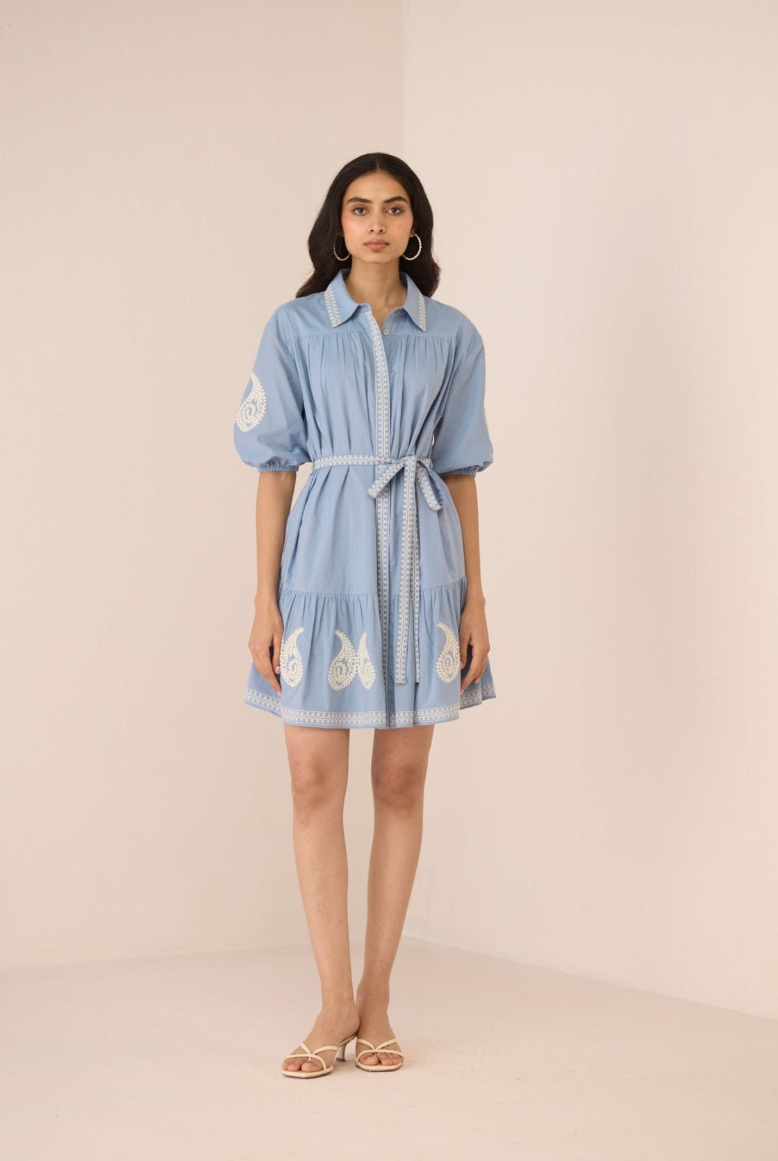Woman wearing a light blue dress with butterfly patterns on a beige background Calling June