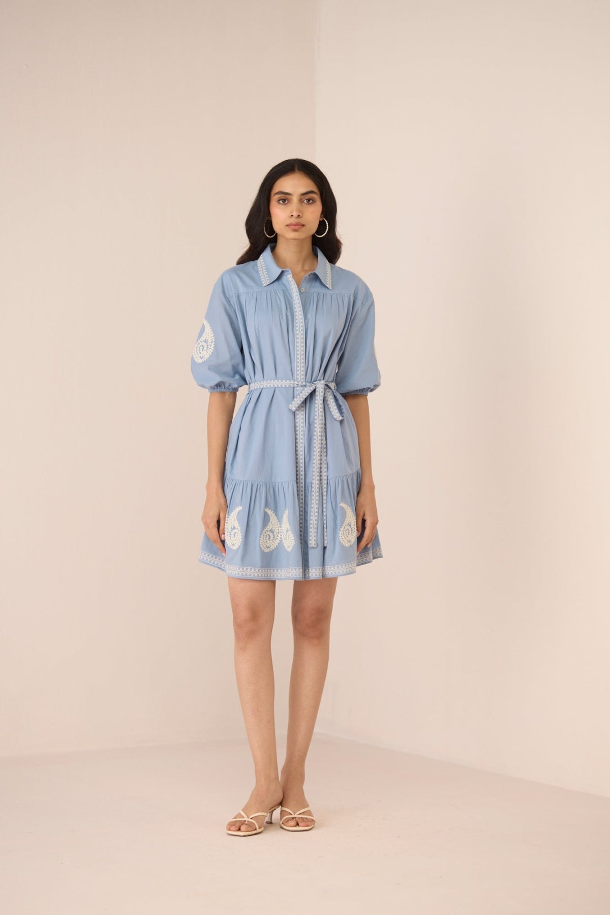 Woman wearing a light blue dress with butterfly patterns on a beige background Calling June