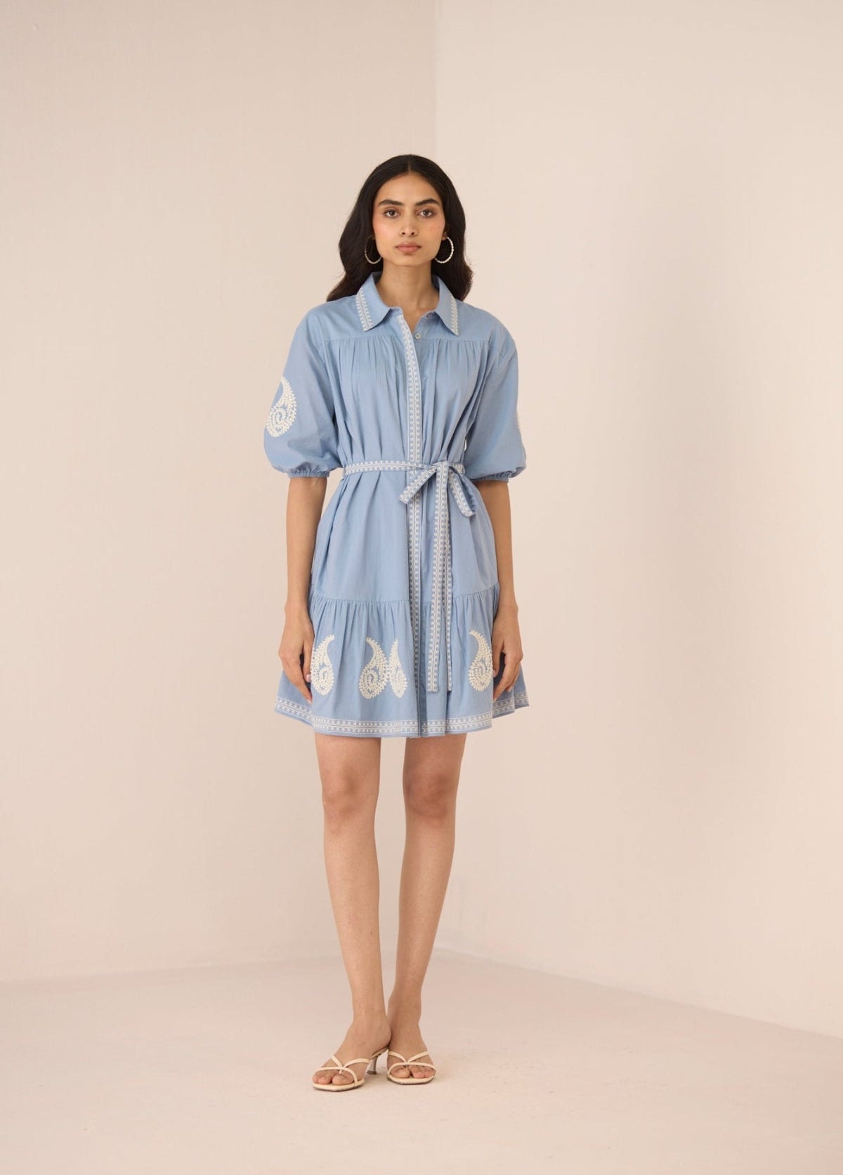 Woman wearing a light blue dress with butterfly patterns on a beige background Calling June
