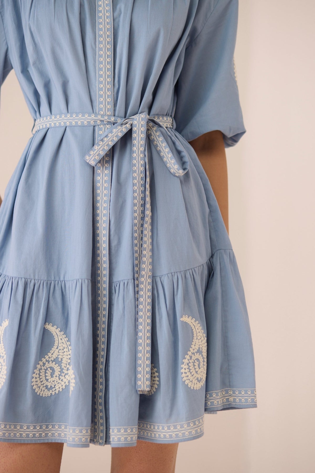Light blue dress with white embroidery on a beige background Calling June