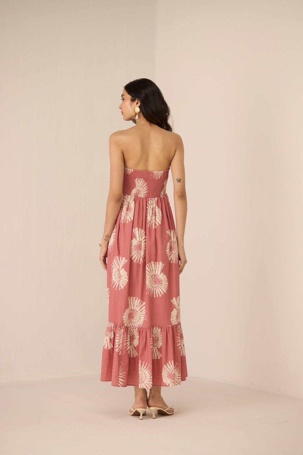 Woman wearing a pink floral dress against a beige background Calling June