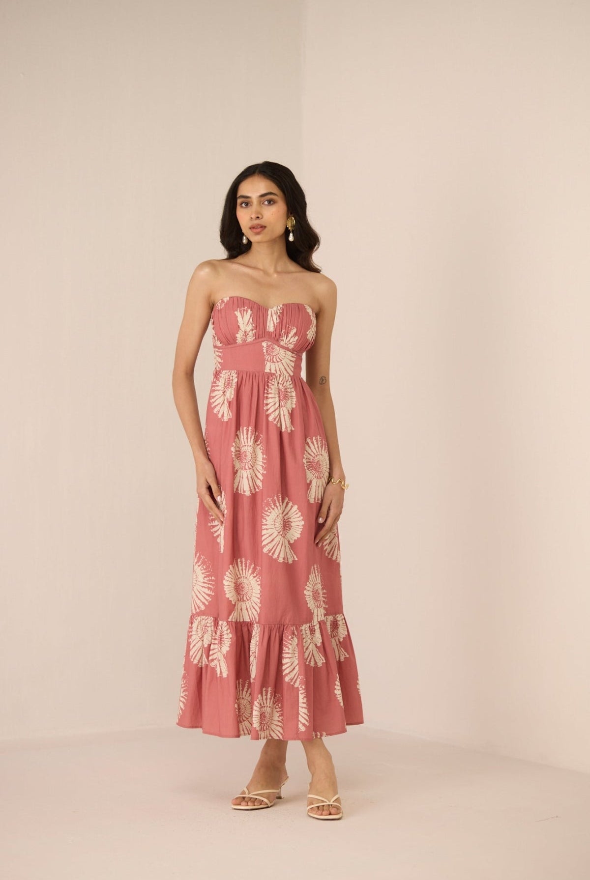Woman wearing a pink strapless dress with floral pattern on a beige background Calling June