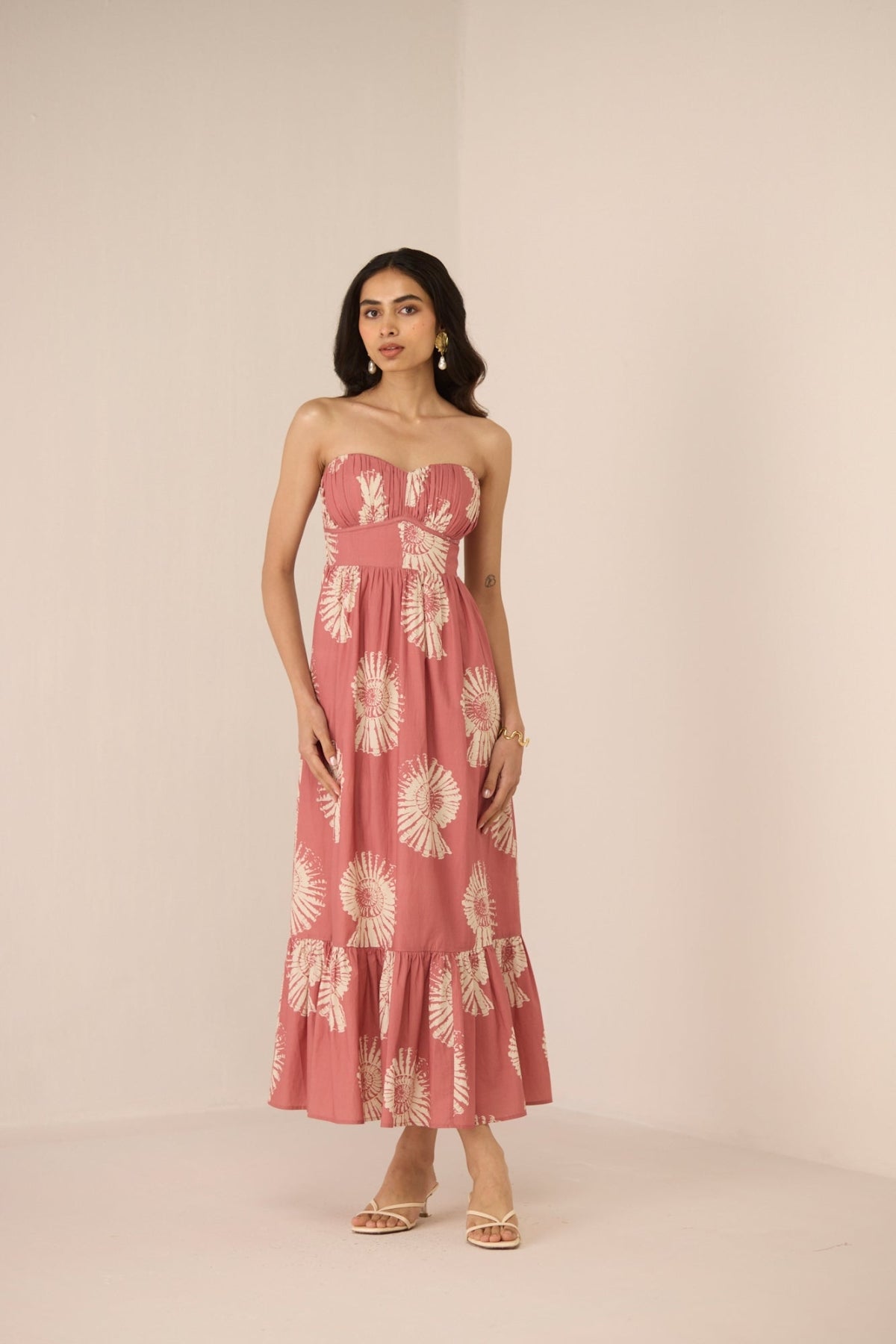 Woman wearing a pink strapless dress with floral pattern on a beige background Calling June