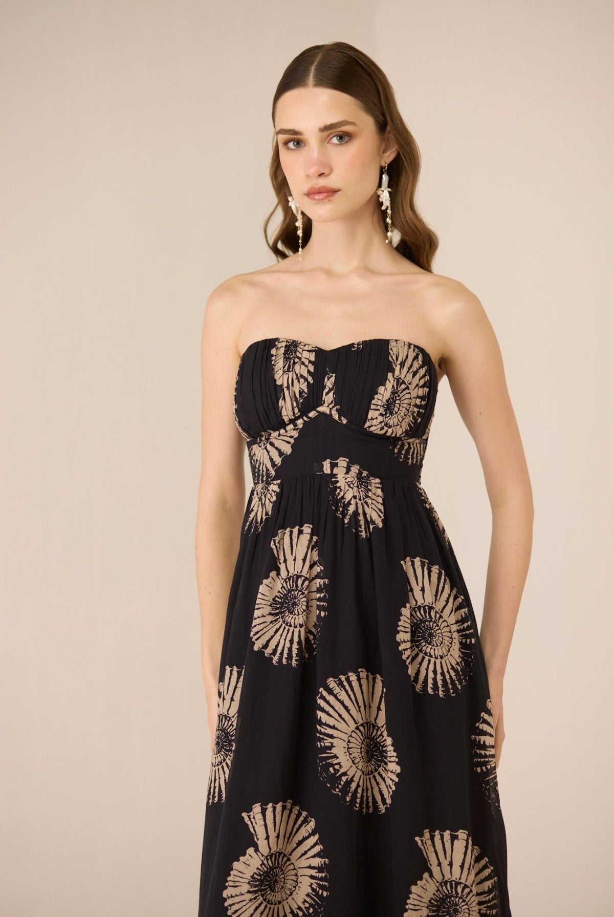 Woman wearing a strapless dress with sunflower pattern on a beige background Calling June