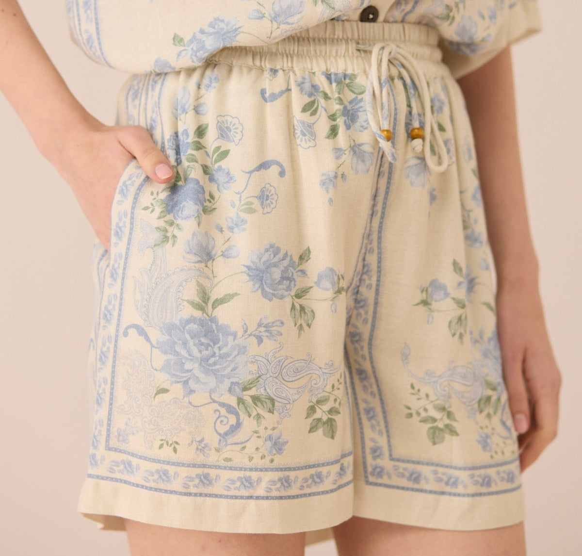 Person wearing a floral outfit with shorts and a top on a plain background Calling June