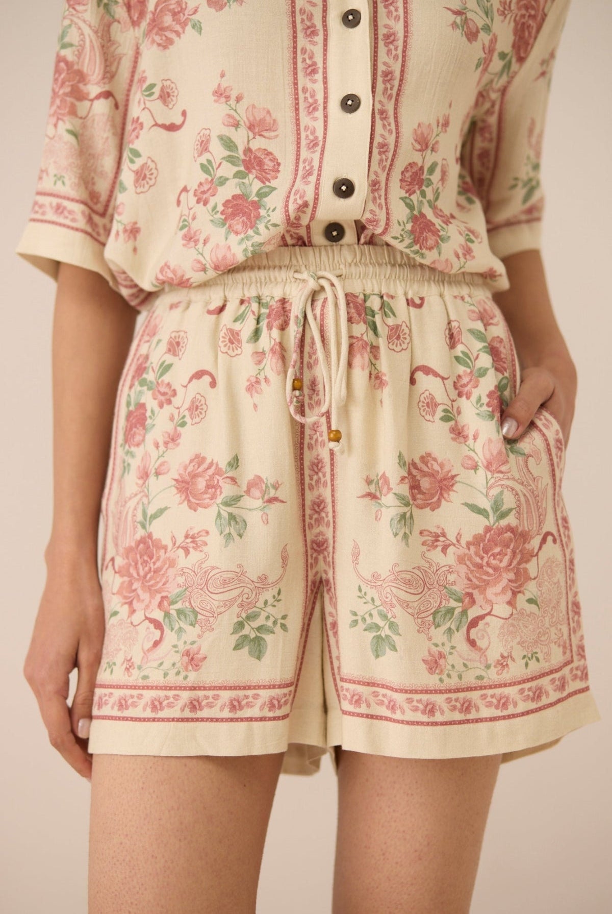 Person wearing a floral patterned outfit with a beige background Calling June