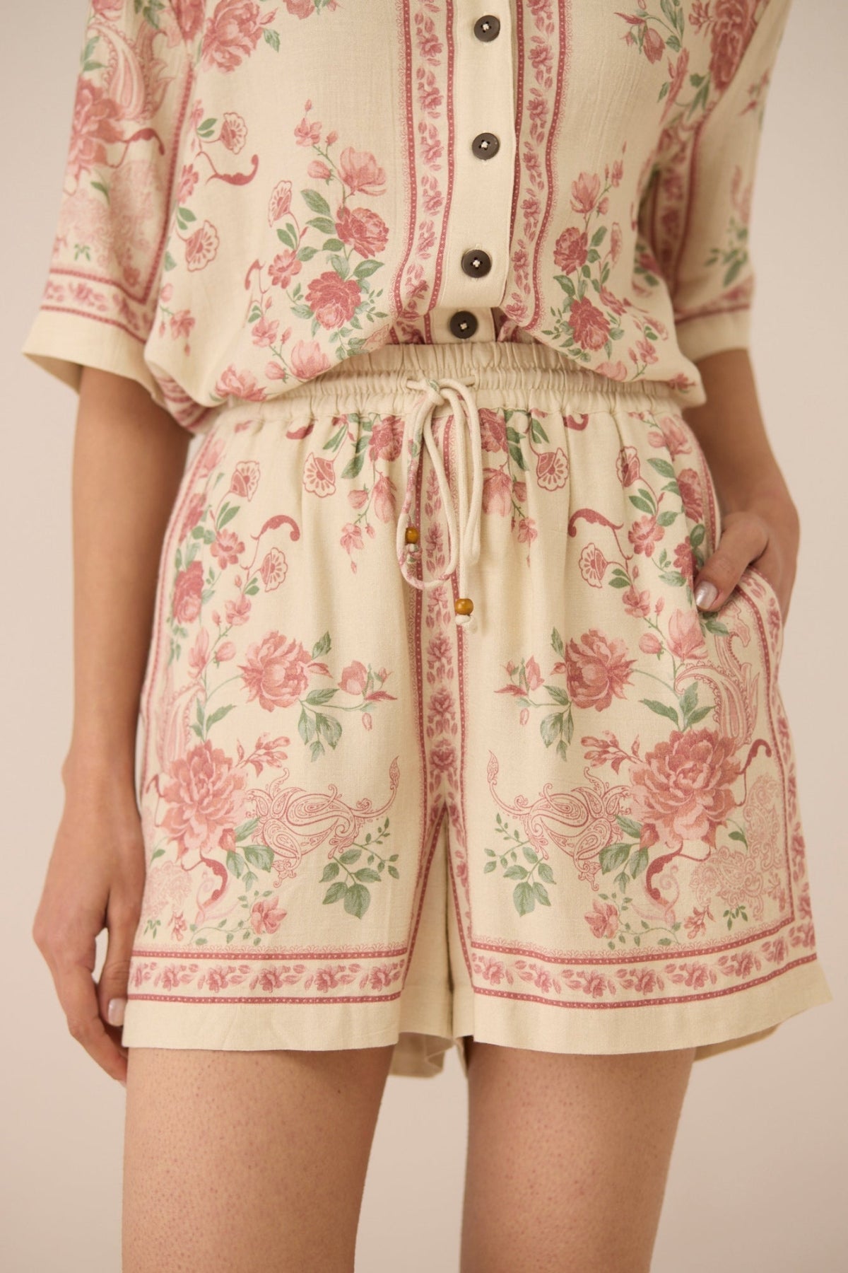 Person wearing a floral patterned outfit with a beige background Calling June