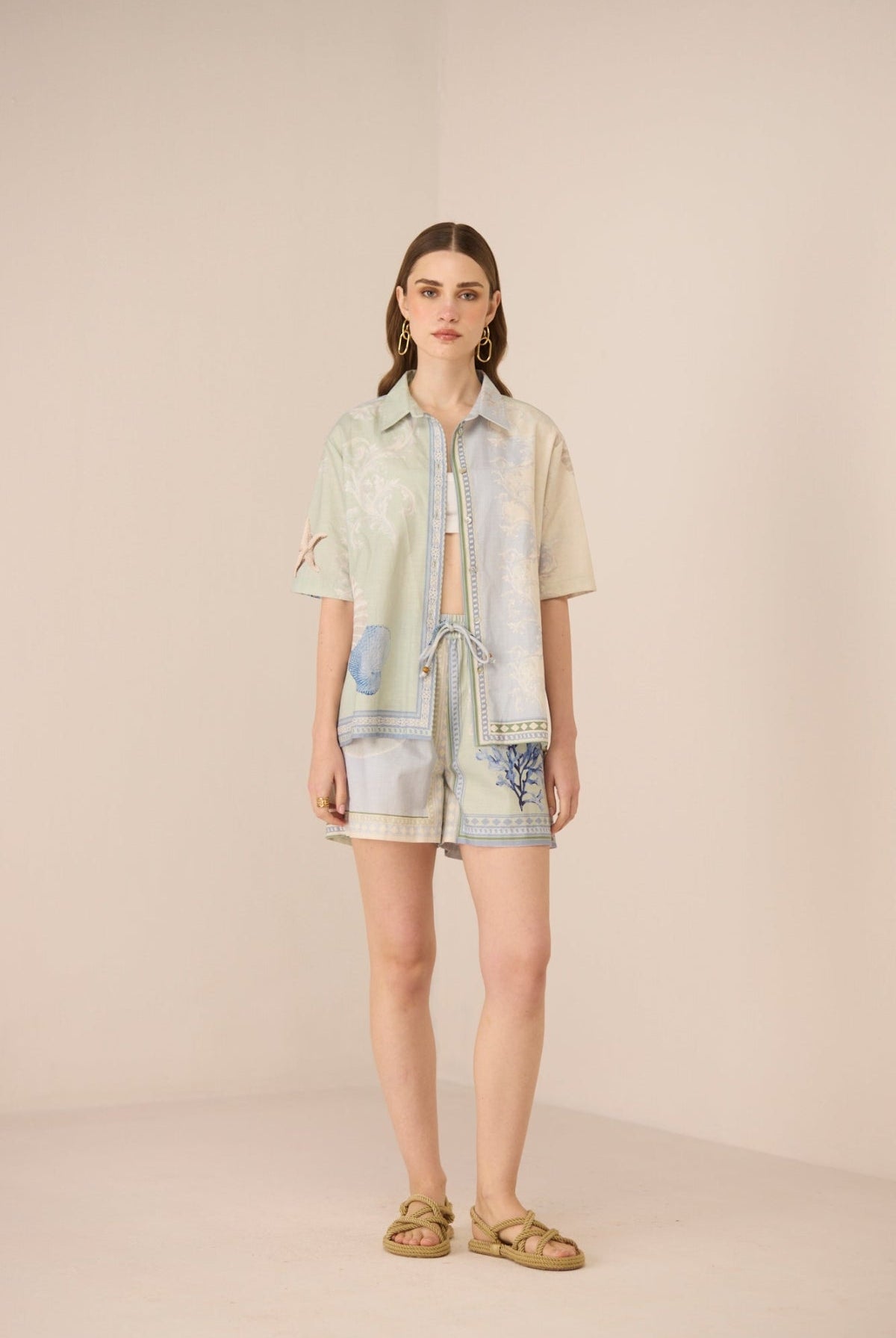 Woman wearing a light-colored outfit with denim accents on a beige background Calling June