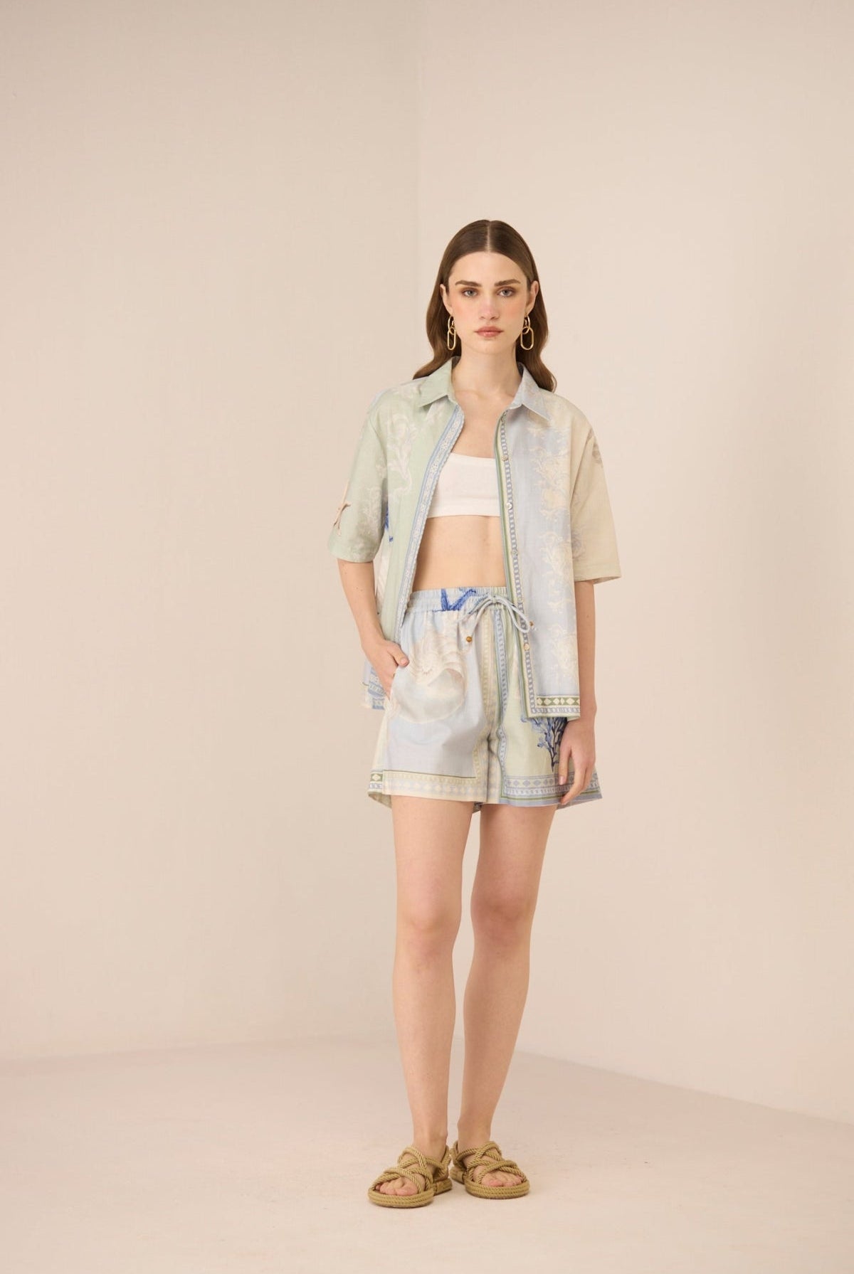 Woman wearing a light-colored outfit with a patterned skirt on a beige background Calling June