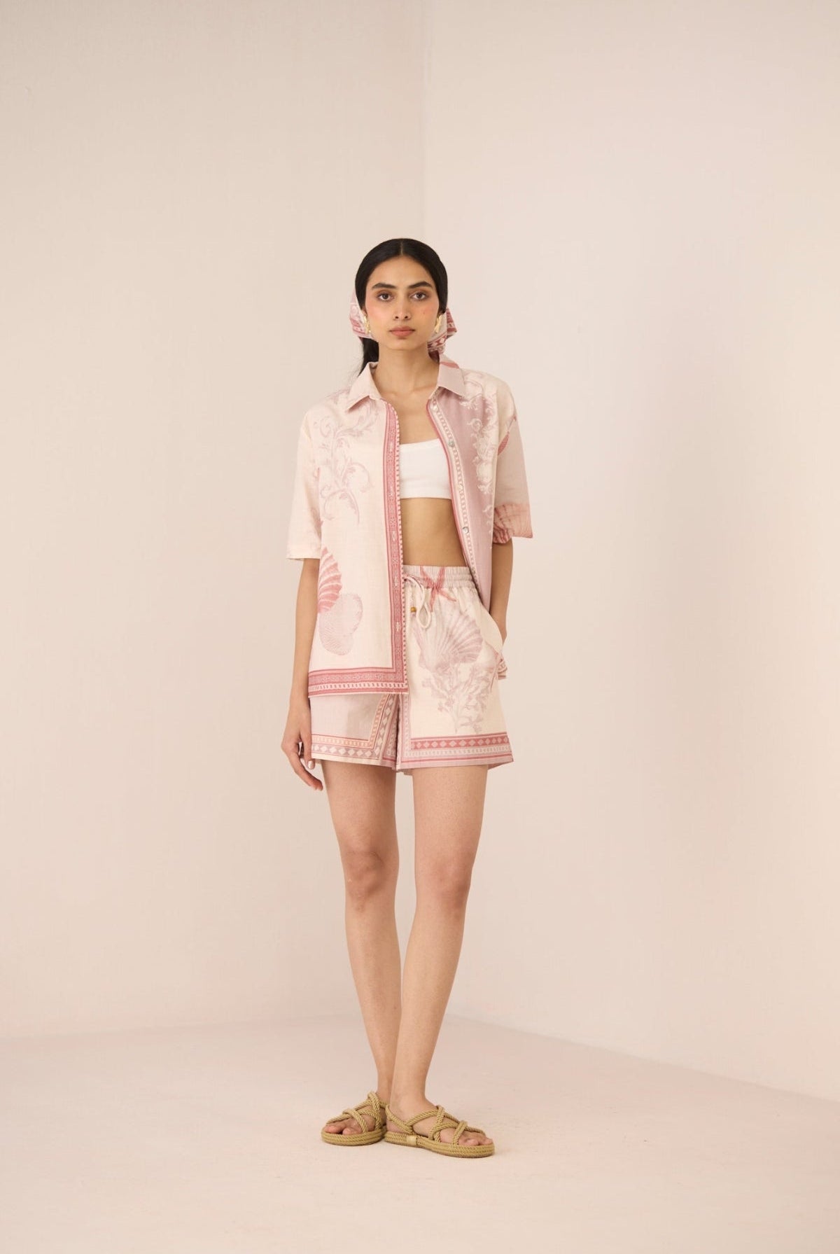 Woman wearing a light pink outfit with a matching jacket on a plain background Calling June