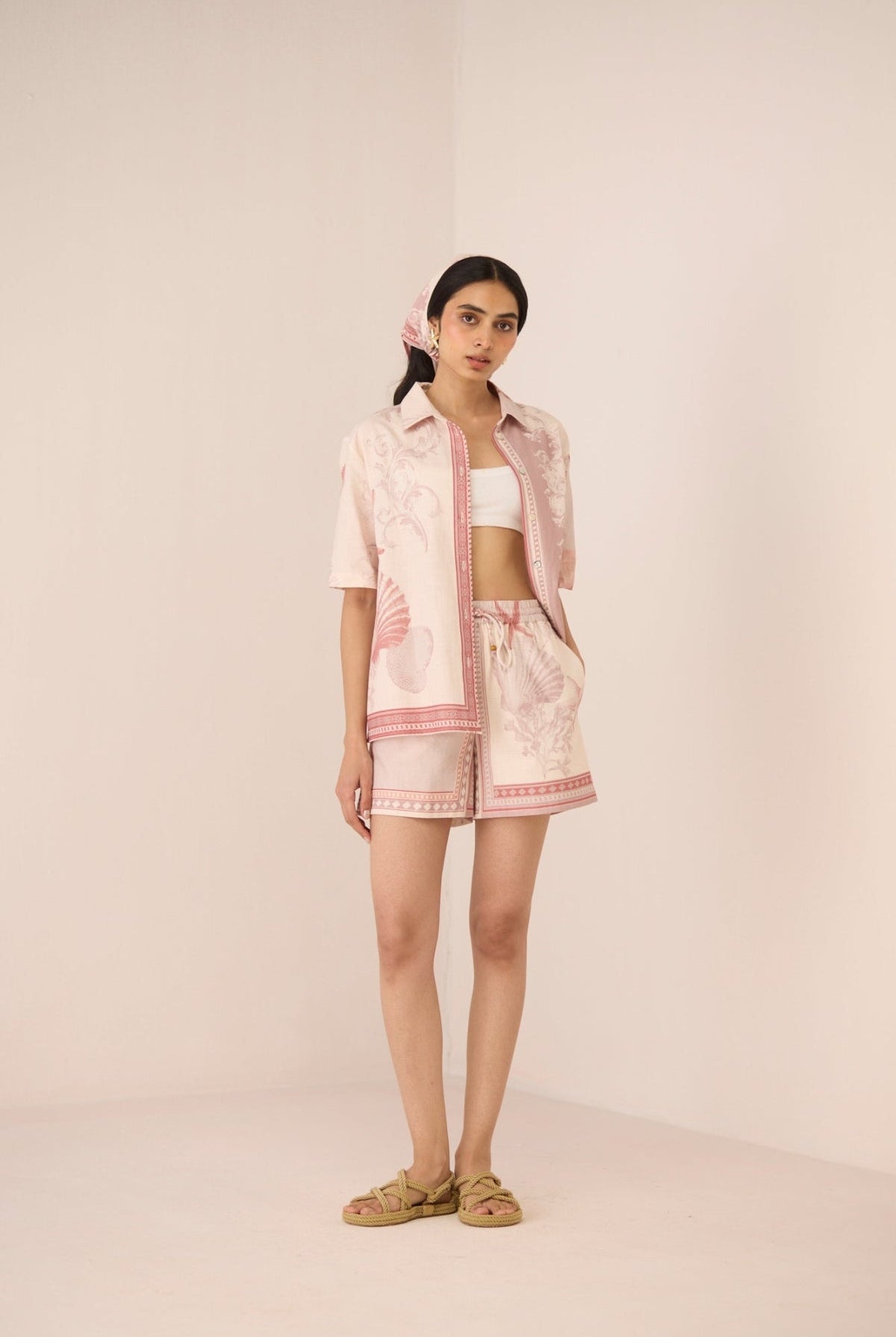 Woman wearing a light pink outfit with a matching scarf on a beige background Calling June