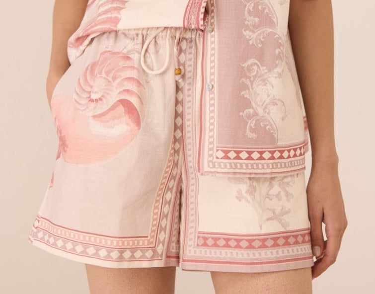 Woman wearing a pink and white patterned outfit with a matching headscarf against a beige background Calling June