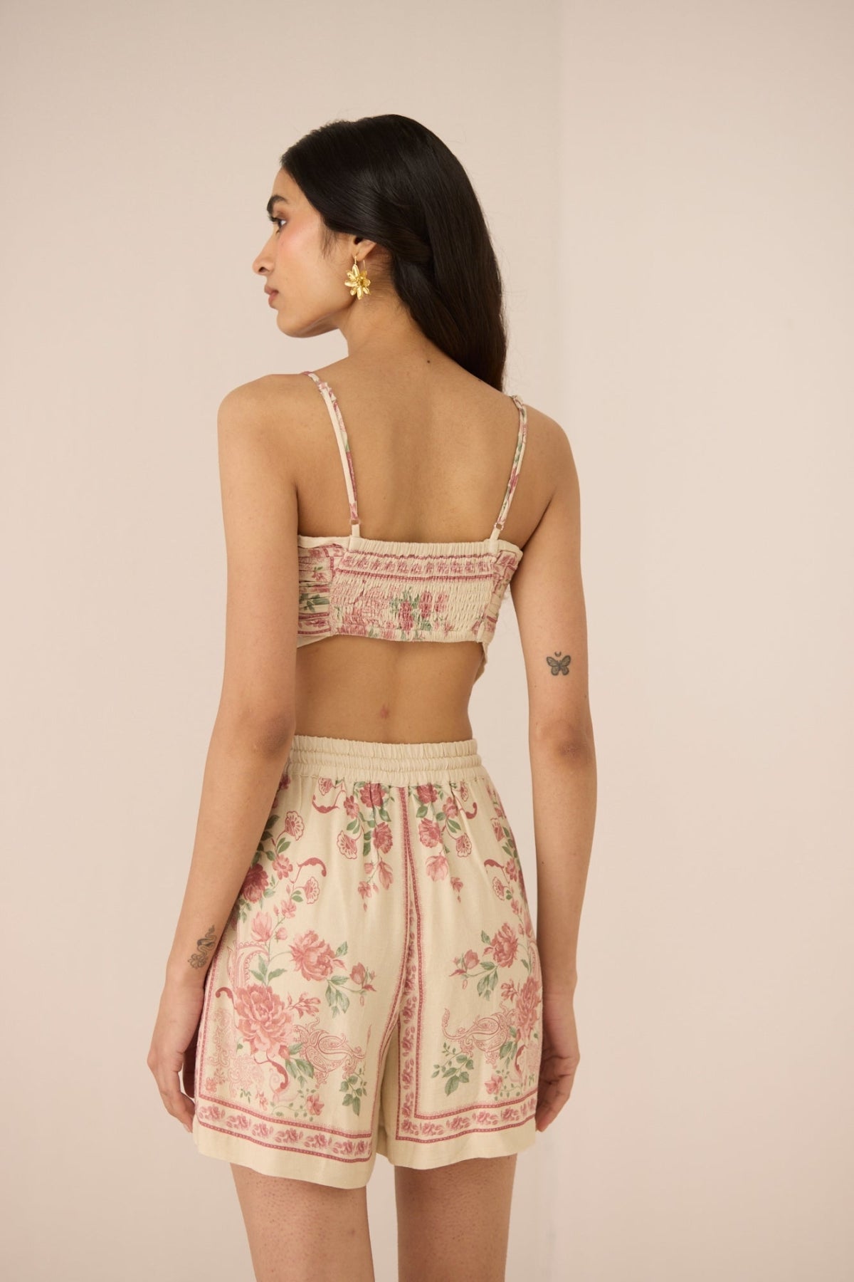 Woman wearing a floral top and shorts set on a beige background Calling June