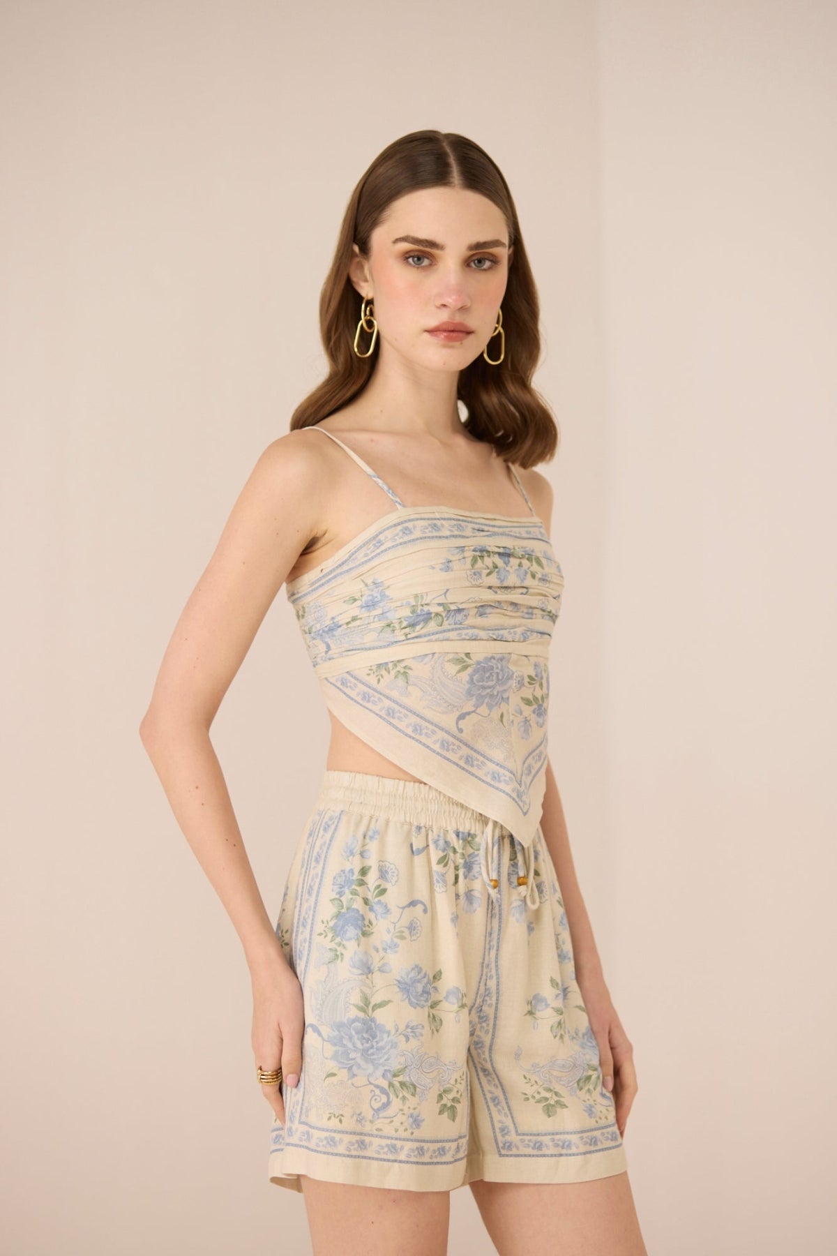 Woman wearing a floral dress and shorts on a beige background Calling June