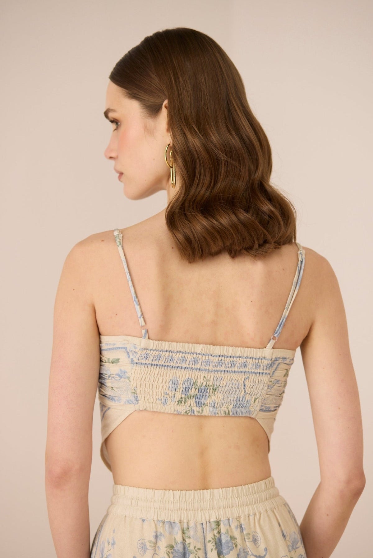 Woman wearing a floral top and skirt set against a beige background Calling June