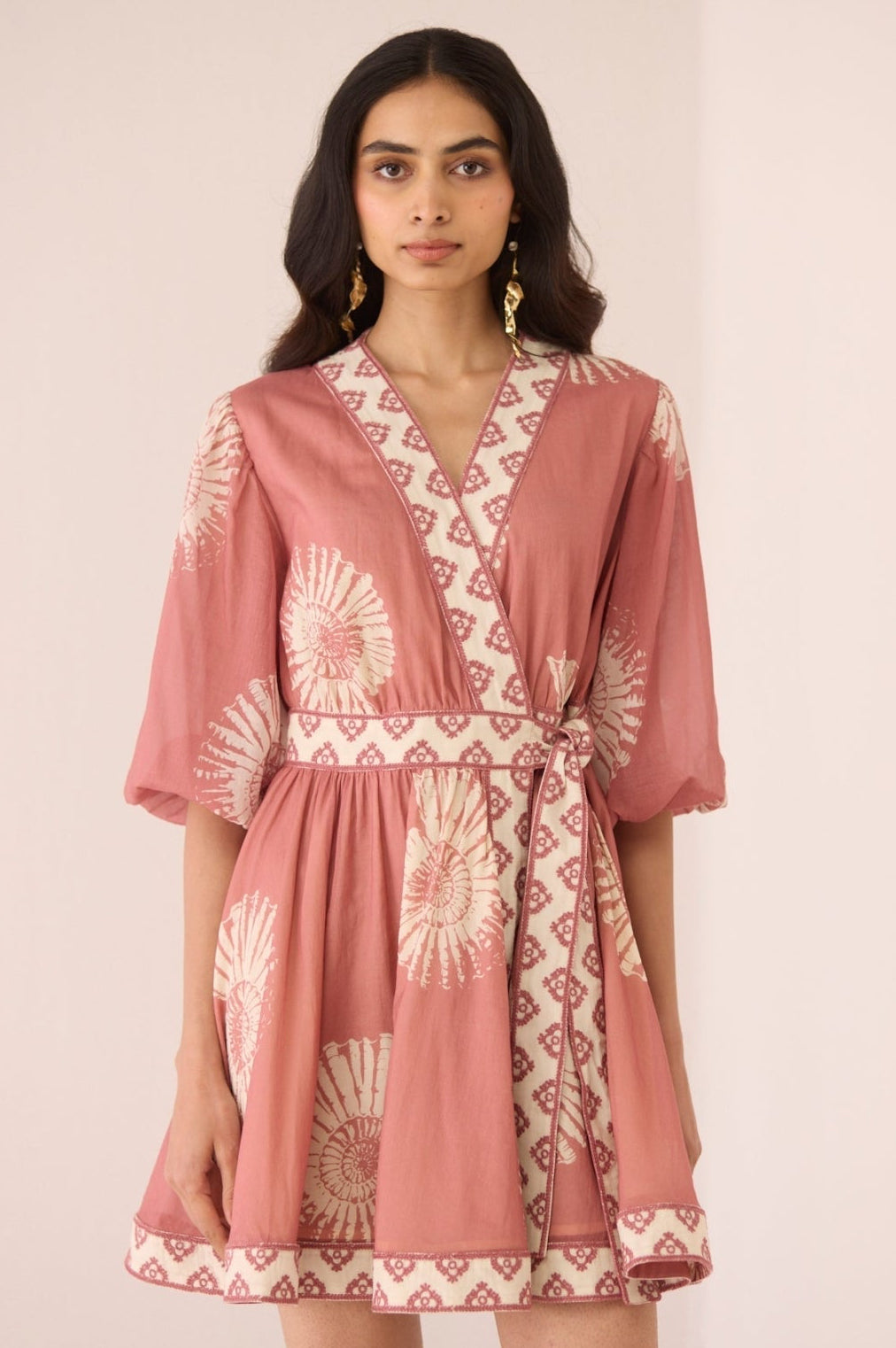 Woman wearing a pink dress with a geometric pattern on a plain background Calling June