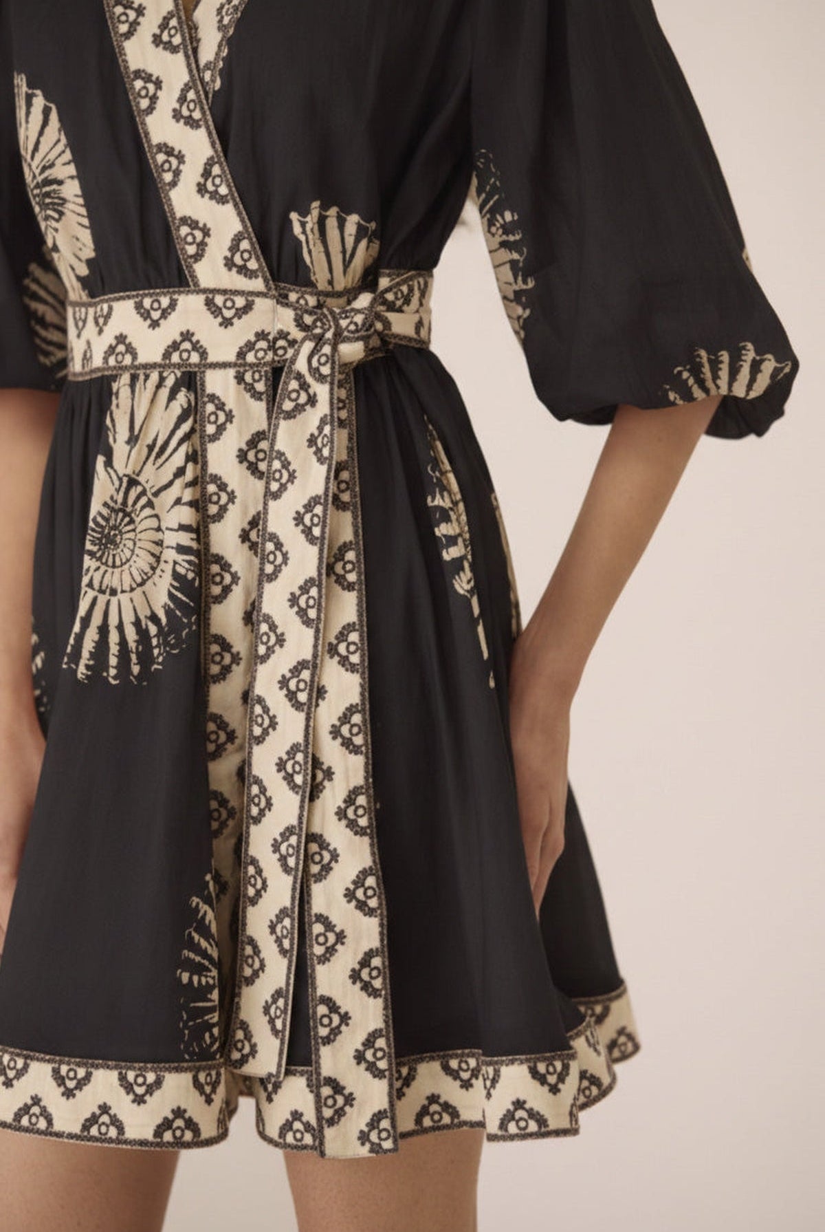 Black and beige patterned dress with a belt on a neutral background Calling June