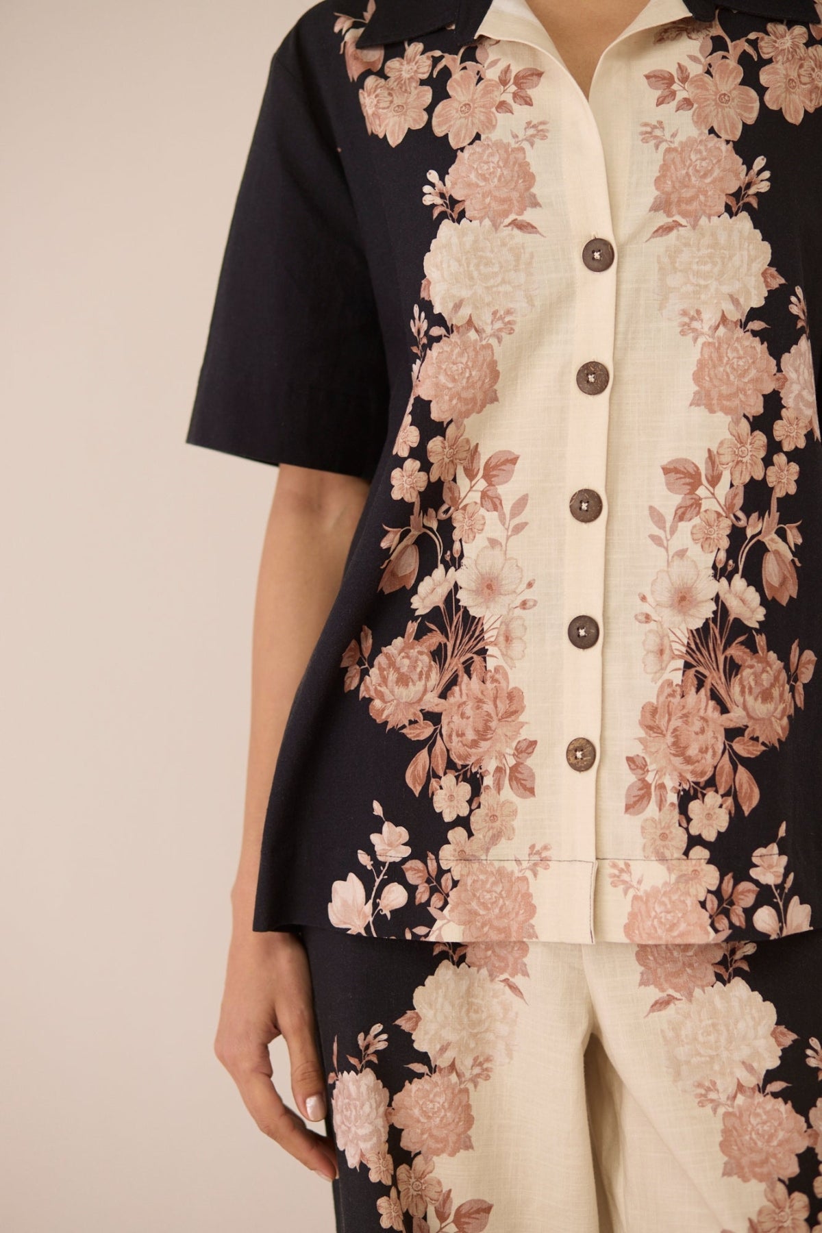 Floral patterned shirt with black, pink, and beige colors on a neutral background Calling June
