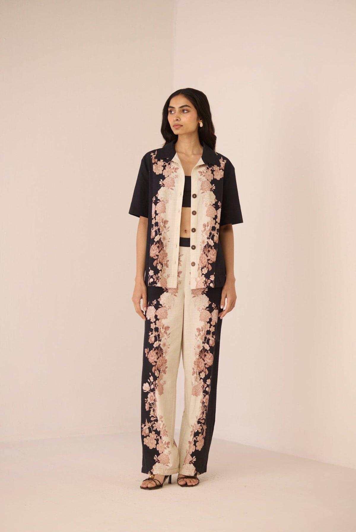 Woman wearing a black and white floral outfit on a beige background Calling June