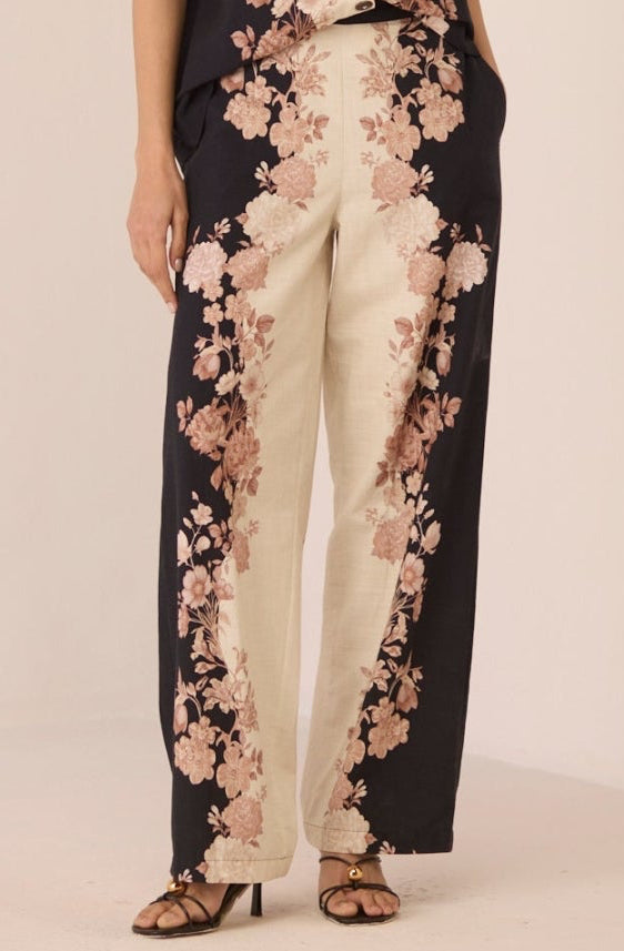 Woman wearing a black and white floral jumpsuit on a beige background Calling June