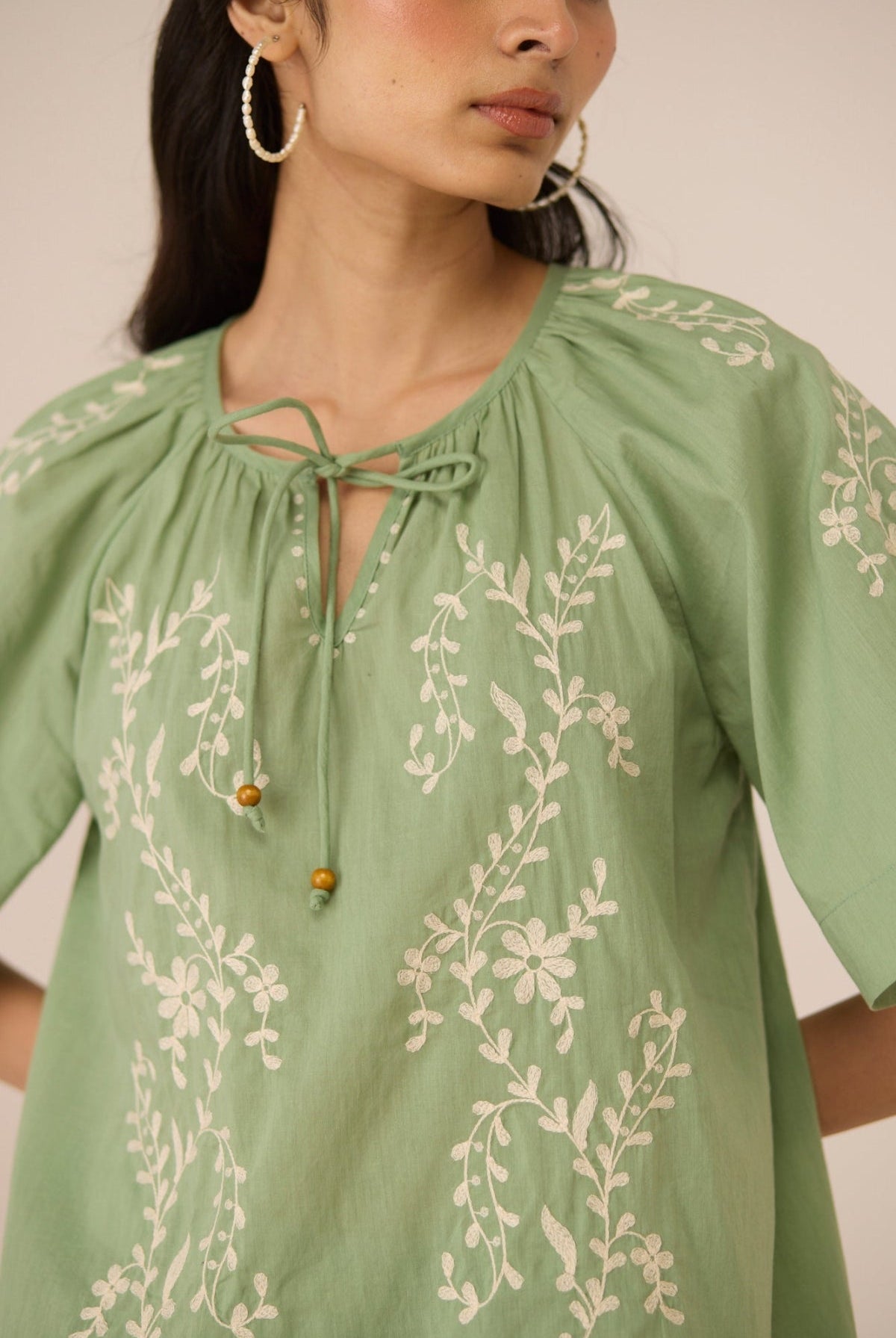 Green embroidered blouse worn by a person on a plain background Calling June