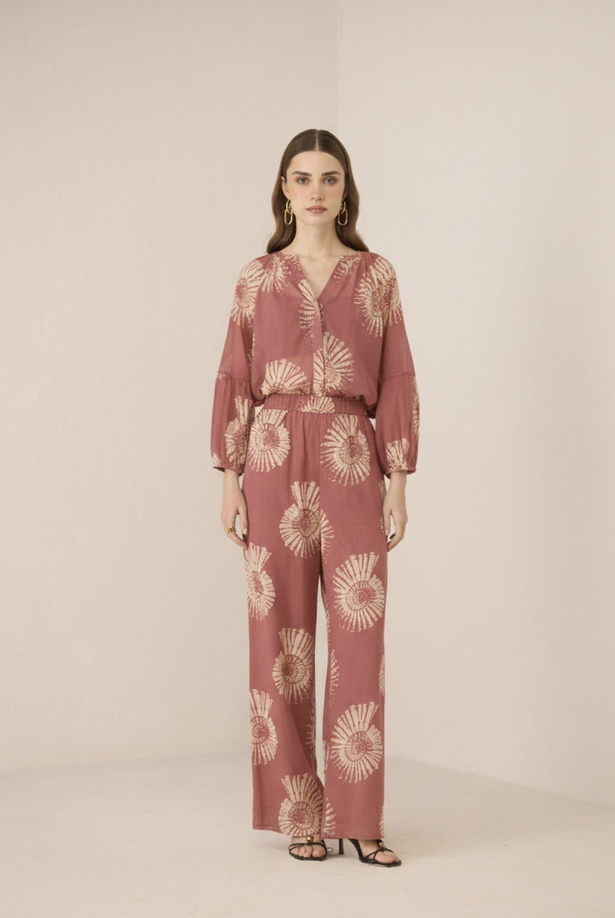 Woman wearing a pink floral jumpsuit on a beige background Calling June