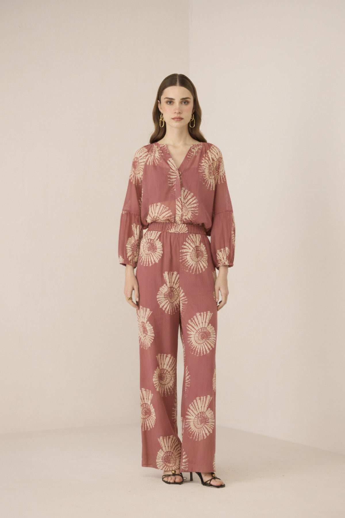 Woman wearing a pink floral jumpsuit on a beige background Calling June