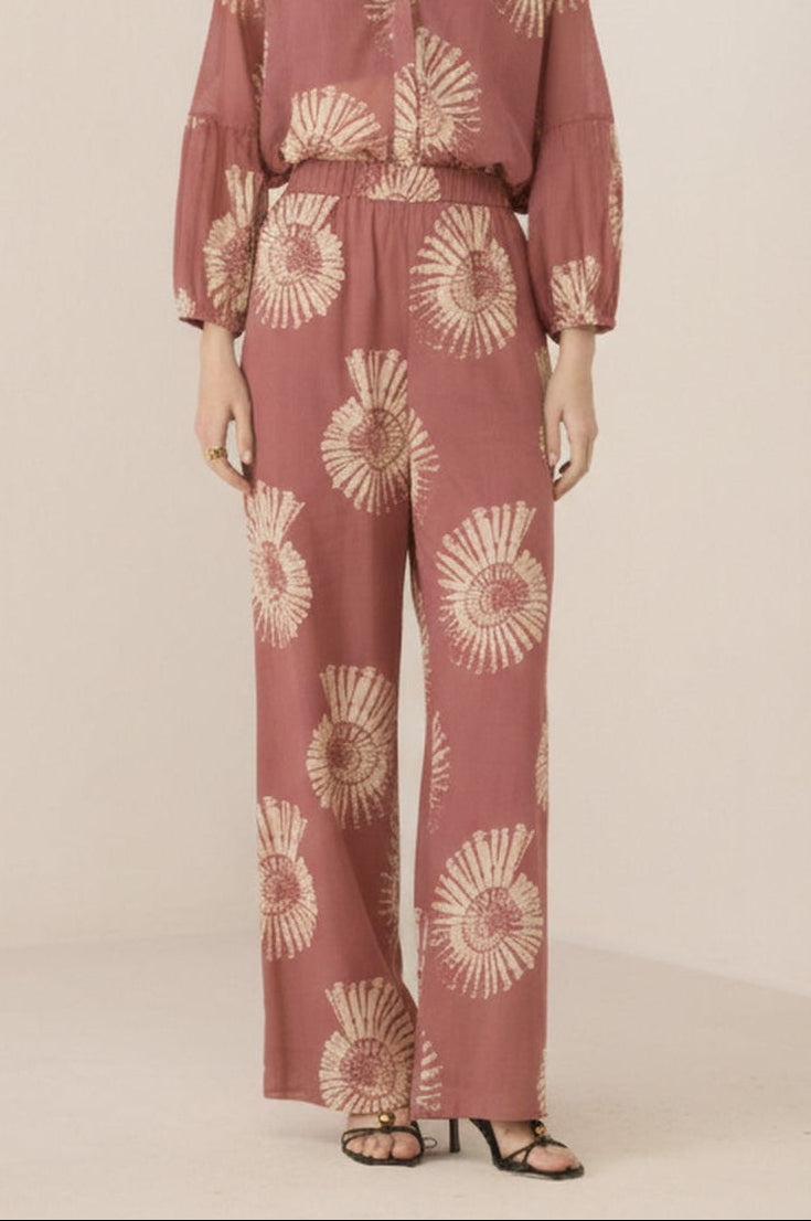 Woman wearing a pink floral jumpsuit on a beige background Calling June