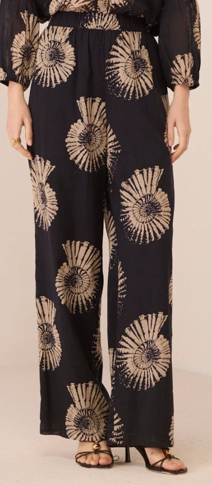 Woman wearing a black floral patterned outfit on a beige background Calling June