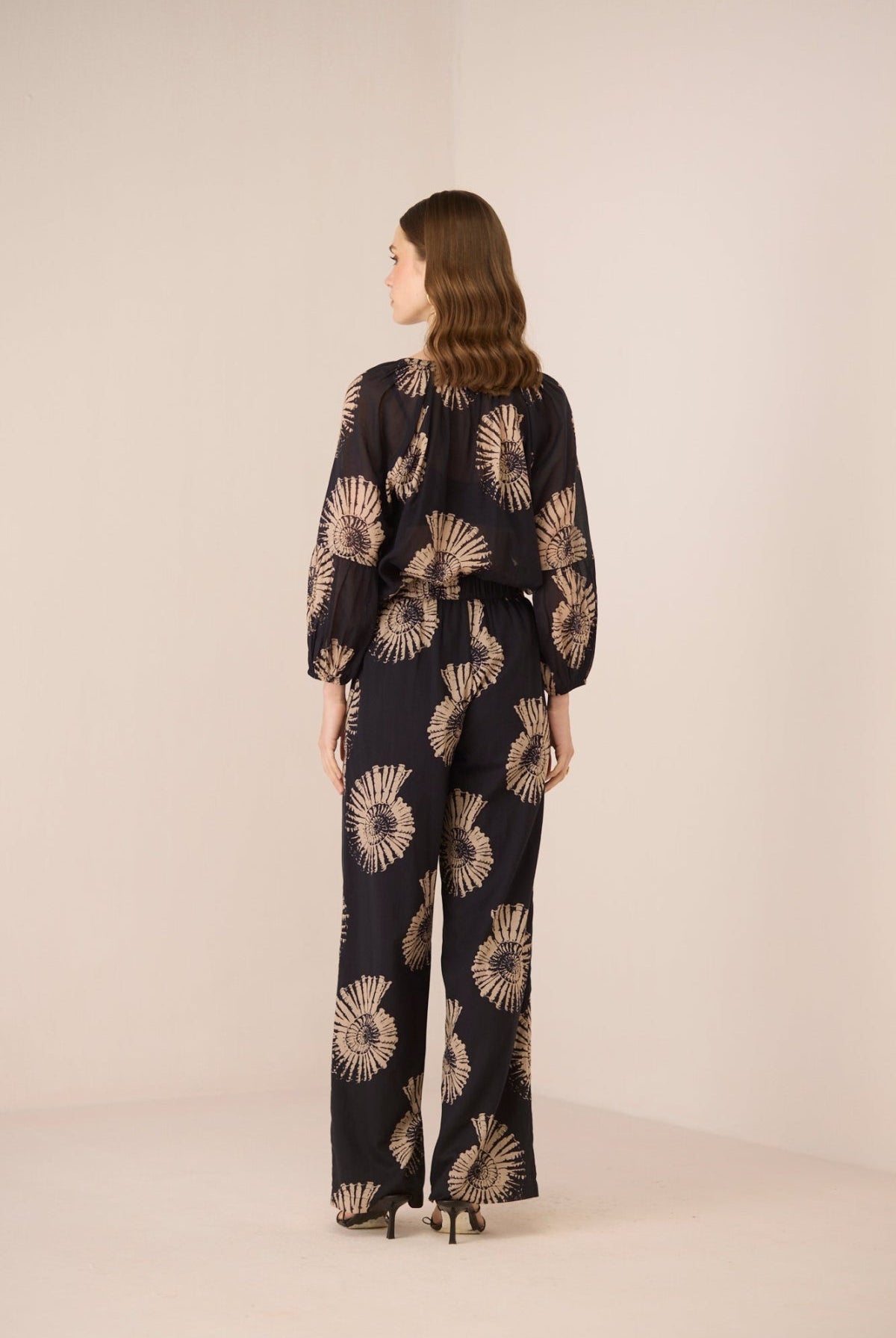 Woman wearing a black floral patterned outfit on a beige background Calling June