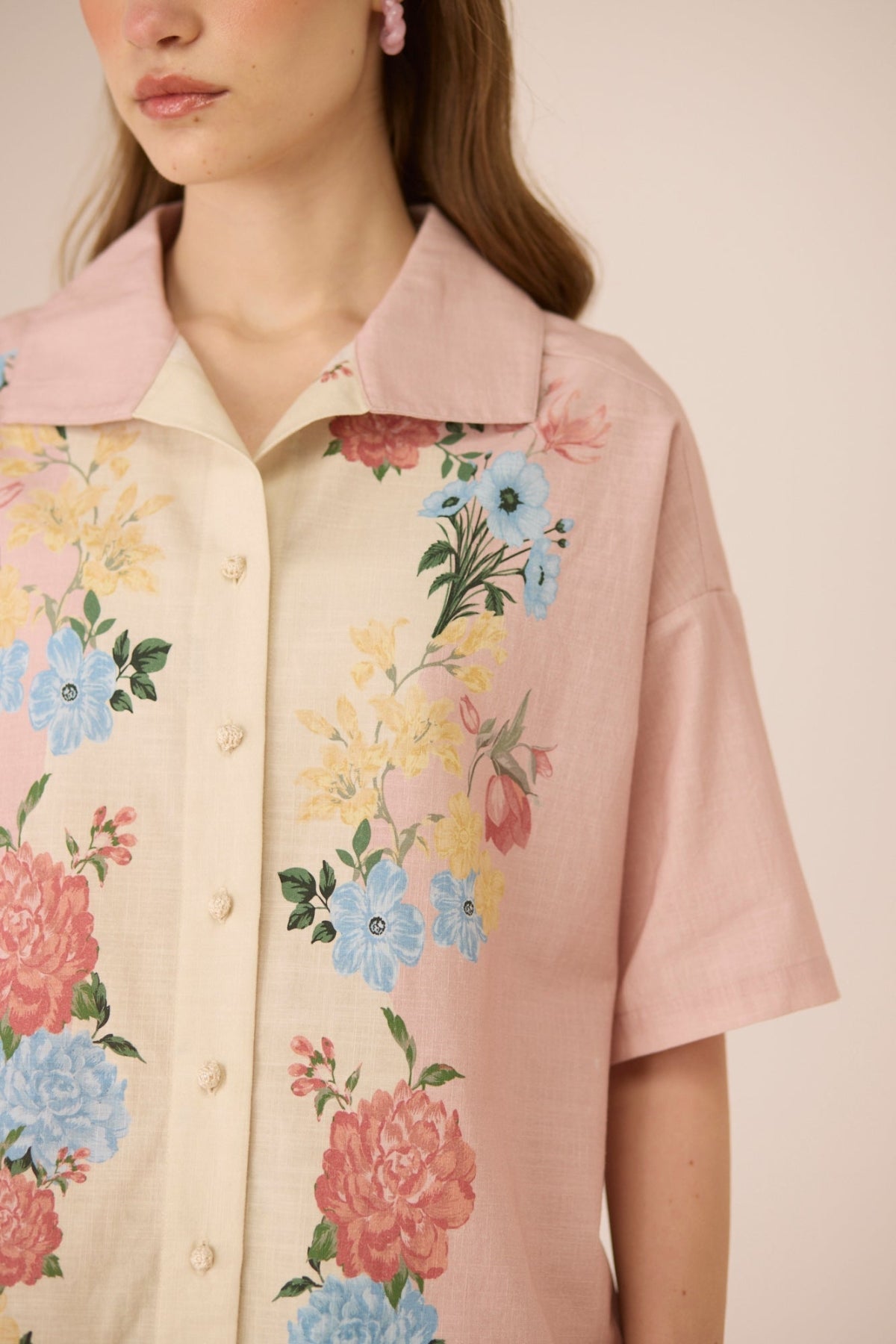 Woman wearing a floral blouse with a soft pink background Calling June