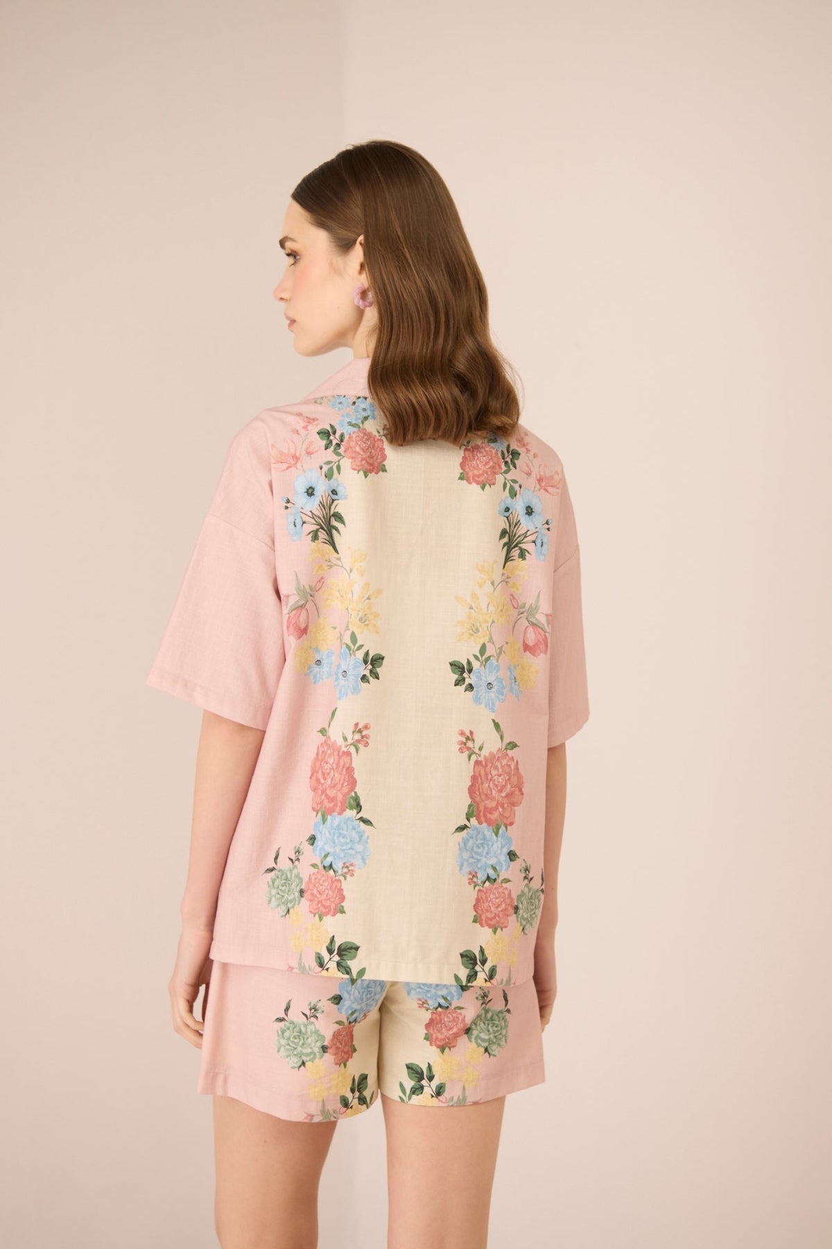 Woman wearing a floral shorts set with a beige background Calling June