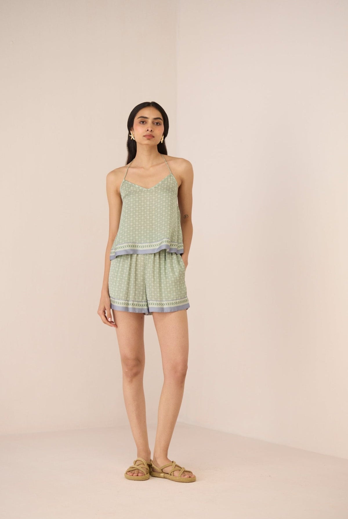 Woman wearing a light green patterned romper on a beige background Calling June