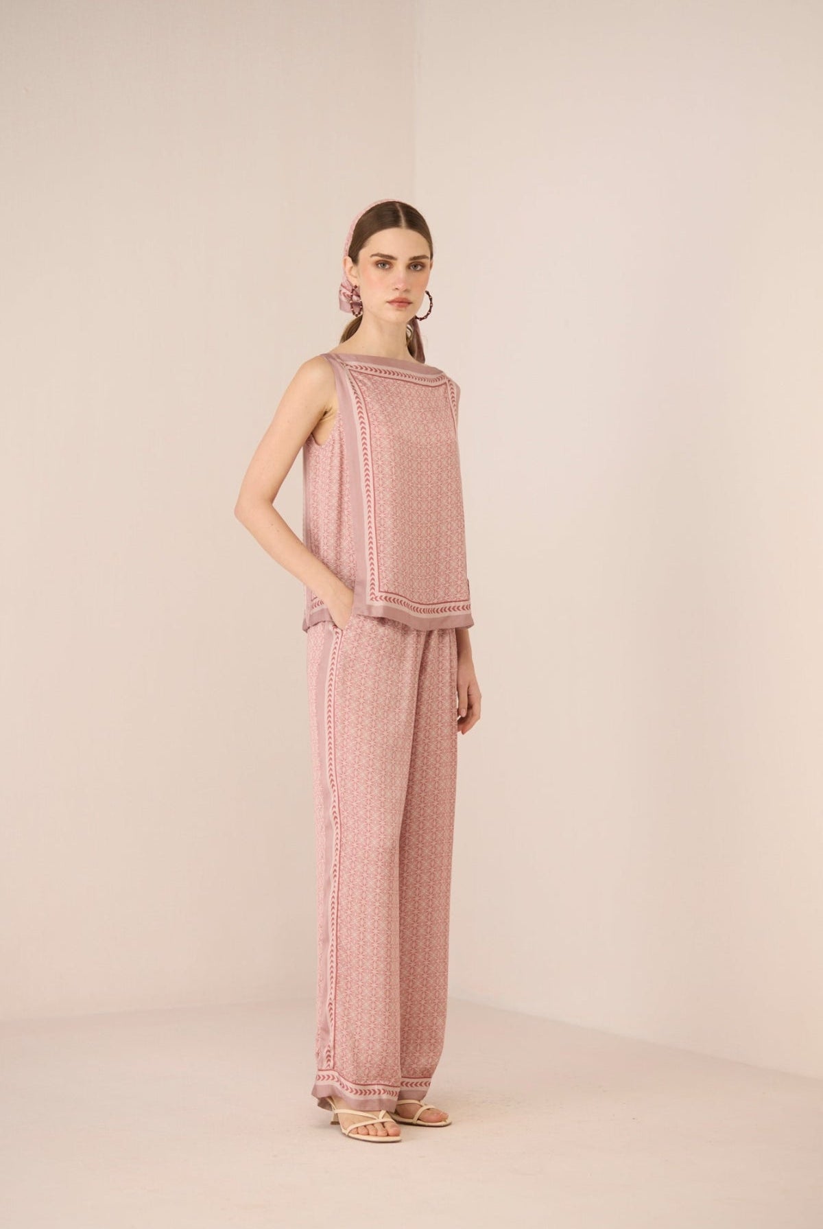 Woman wearing a pink textured outfit on a beige background Calling June