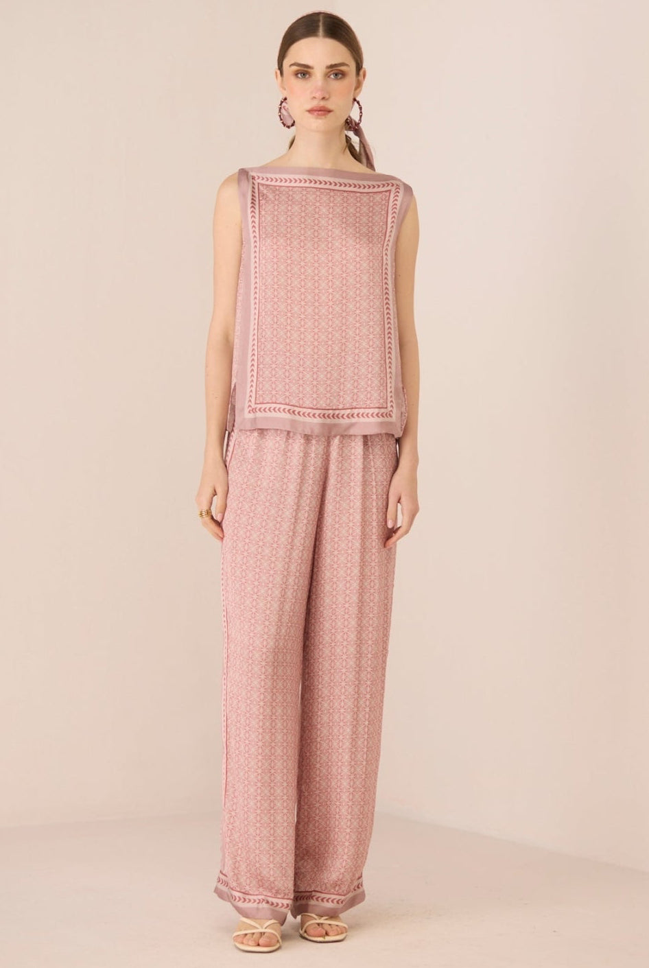 Woman wearing a pink textured sleeveless top and pants on a beige background Calling June