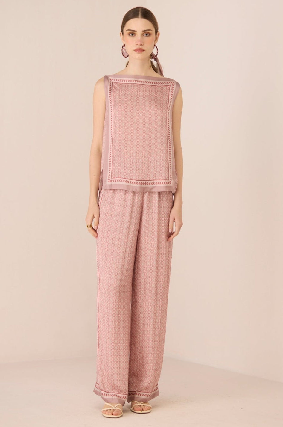 Woman wearing a pink textured sleeveless top and pants on a beige background Calling June
