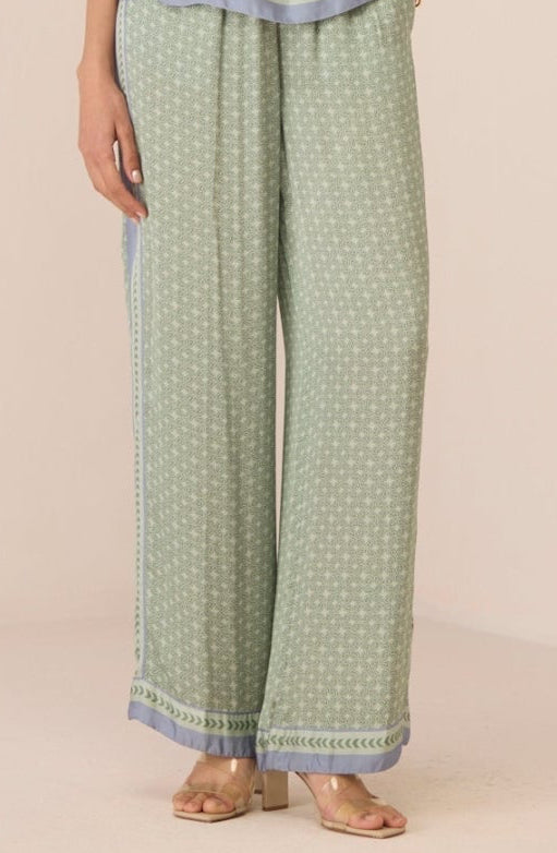 Woman wearing a green patterned outfit with a plain background Calling June