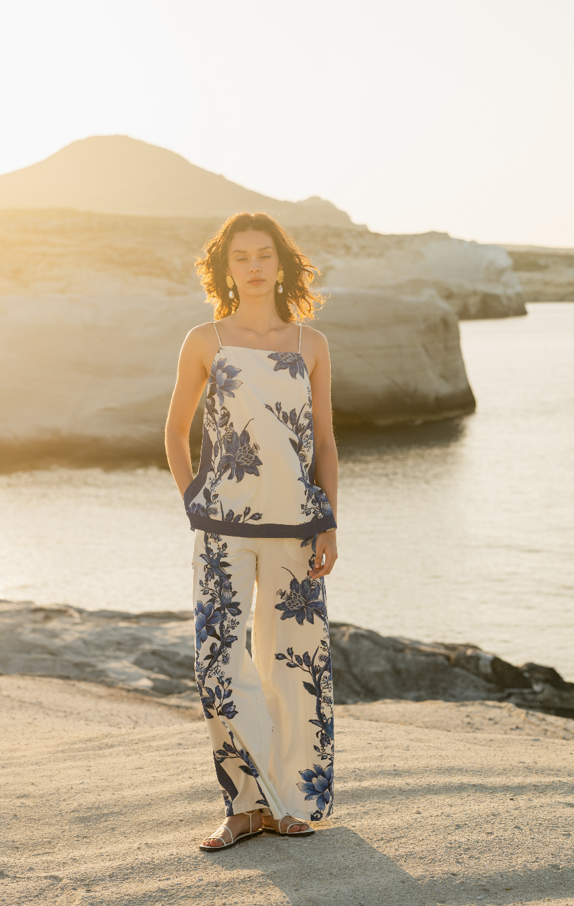 Woman in a floral matching set standing on a beach with rocks and water in the background Calling June
