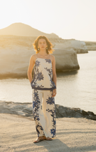 Woman in a floral matching set standing on a beach with rocks and water in the background Calling June