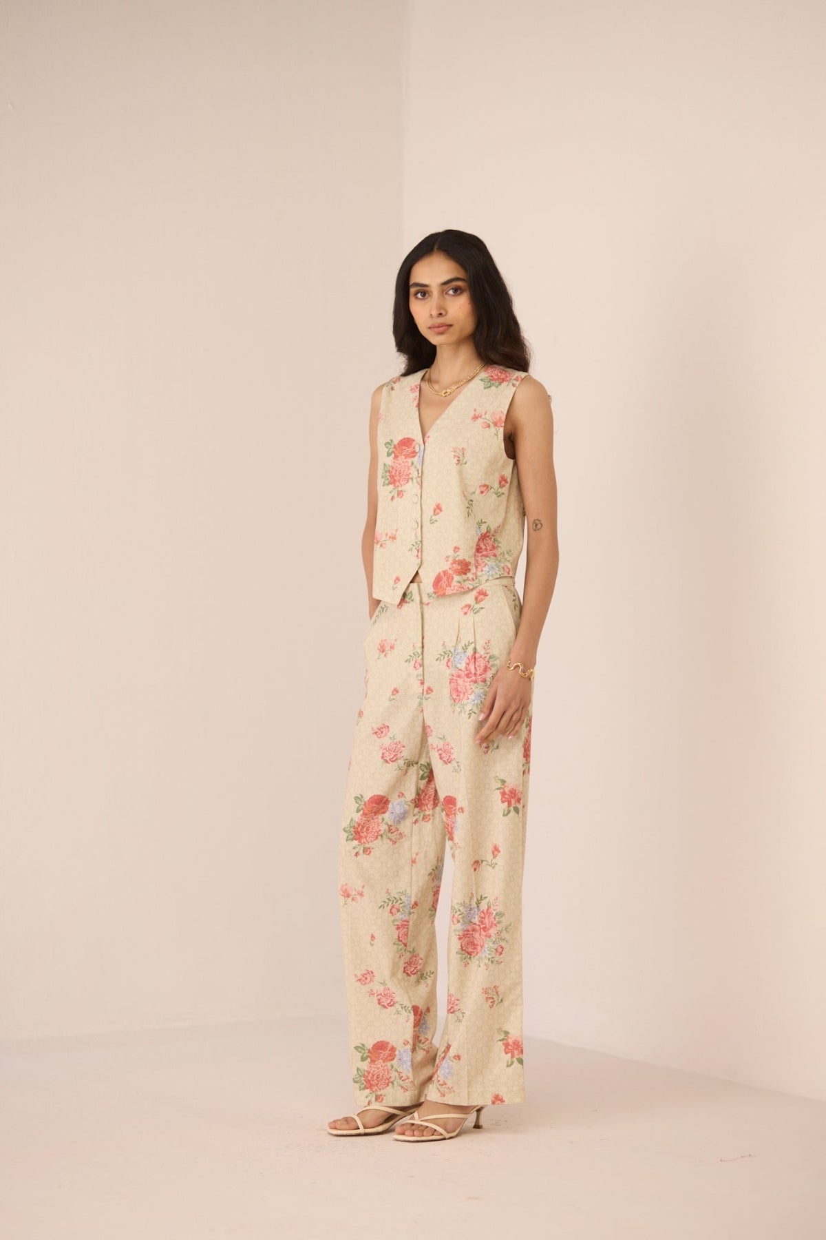 Woman wearing a floral jumpsuit on a plain background Calling June