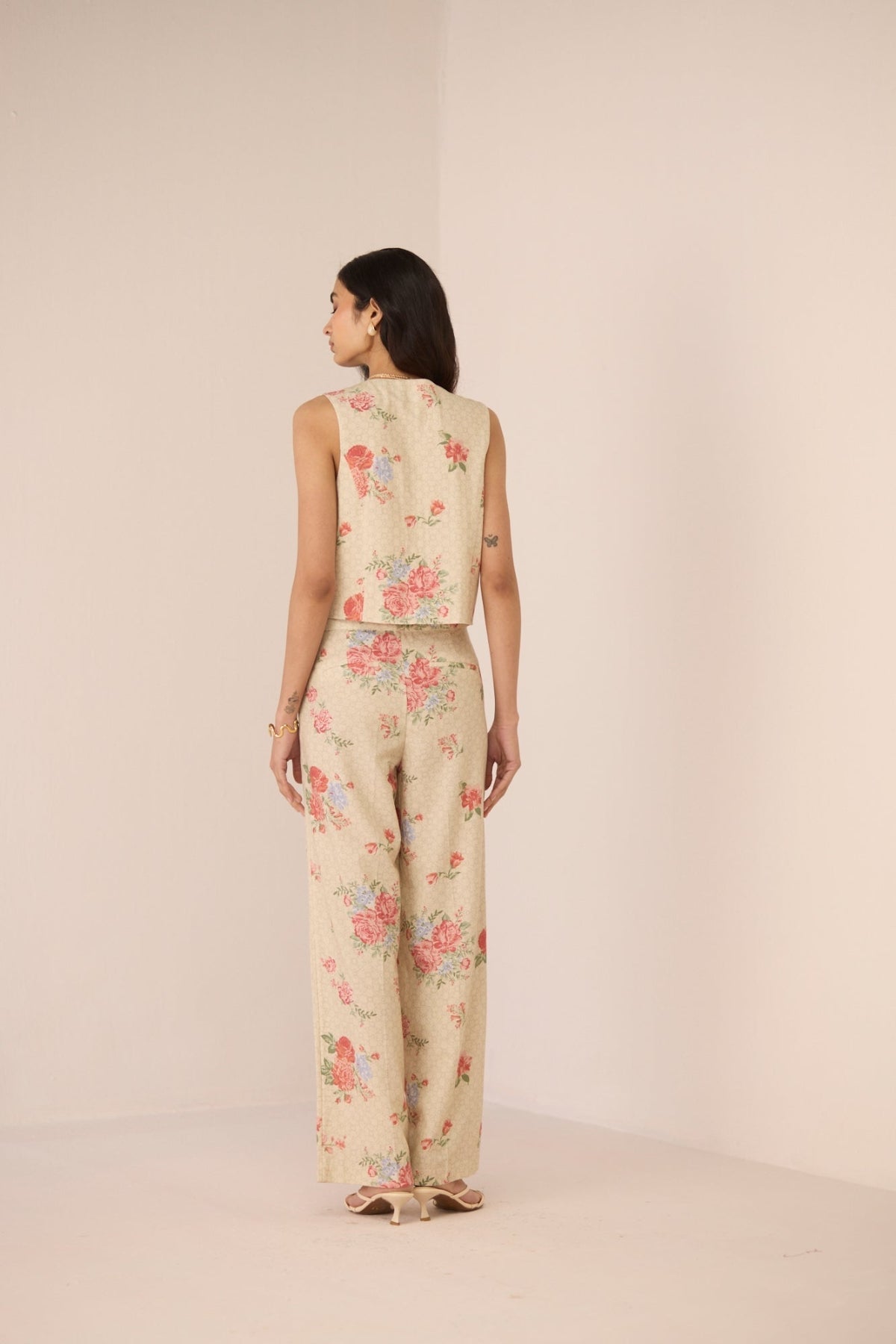 Woman wearing a floral sleeveless top and pants on a beige background Calling June