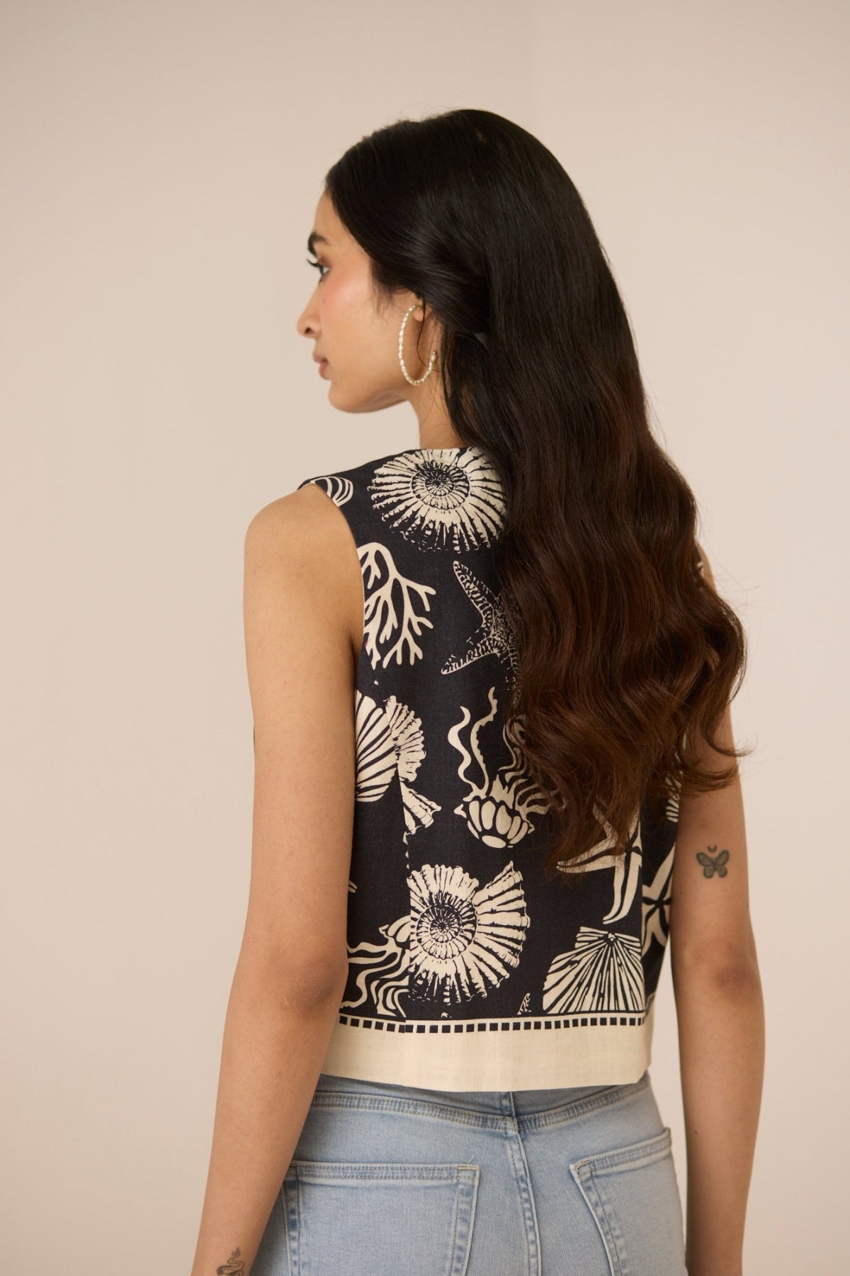 Woman wearing a sleeveless top with a floral pattern on a beige background Calling June