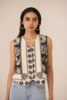 Woman wearing a sleeveless top with black and white pattern against a beige background Calling June